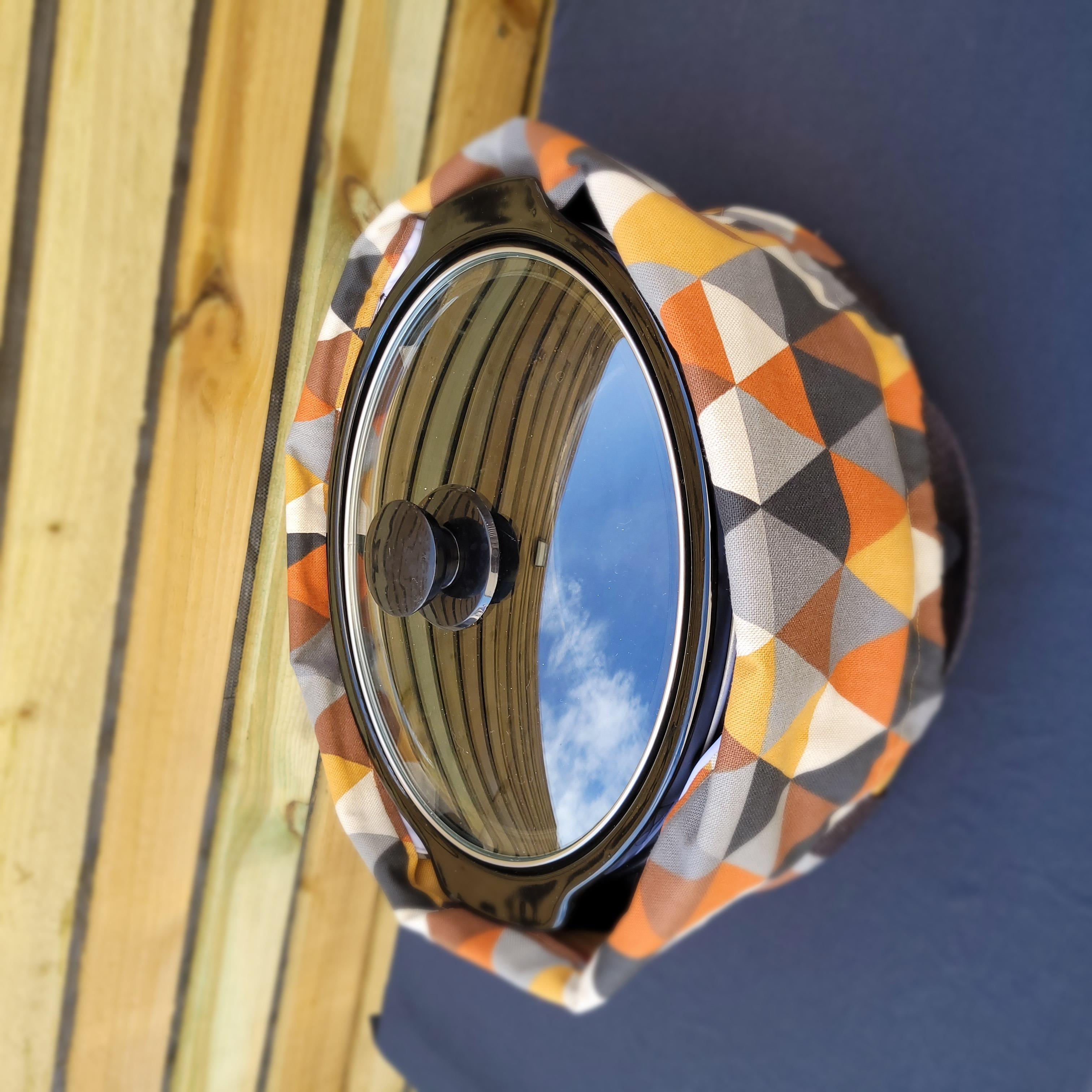 Decorative crock pot carrier bag with geometric pattern on a blue and wooden background. This carrier was made using the warm and cozy slow cooker carrier pattern by Ellie and Mac sewing patterns.