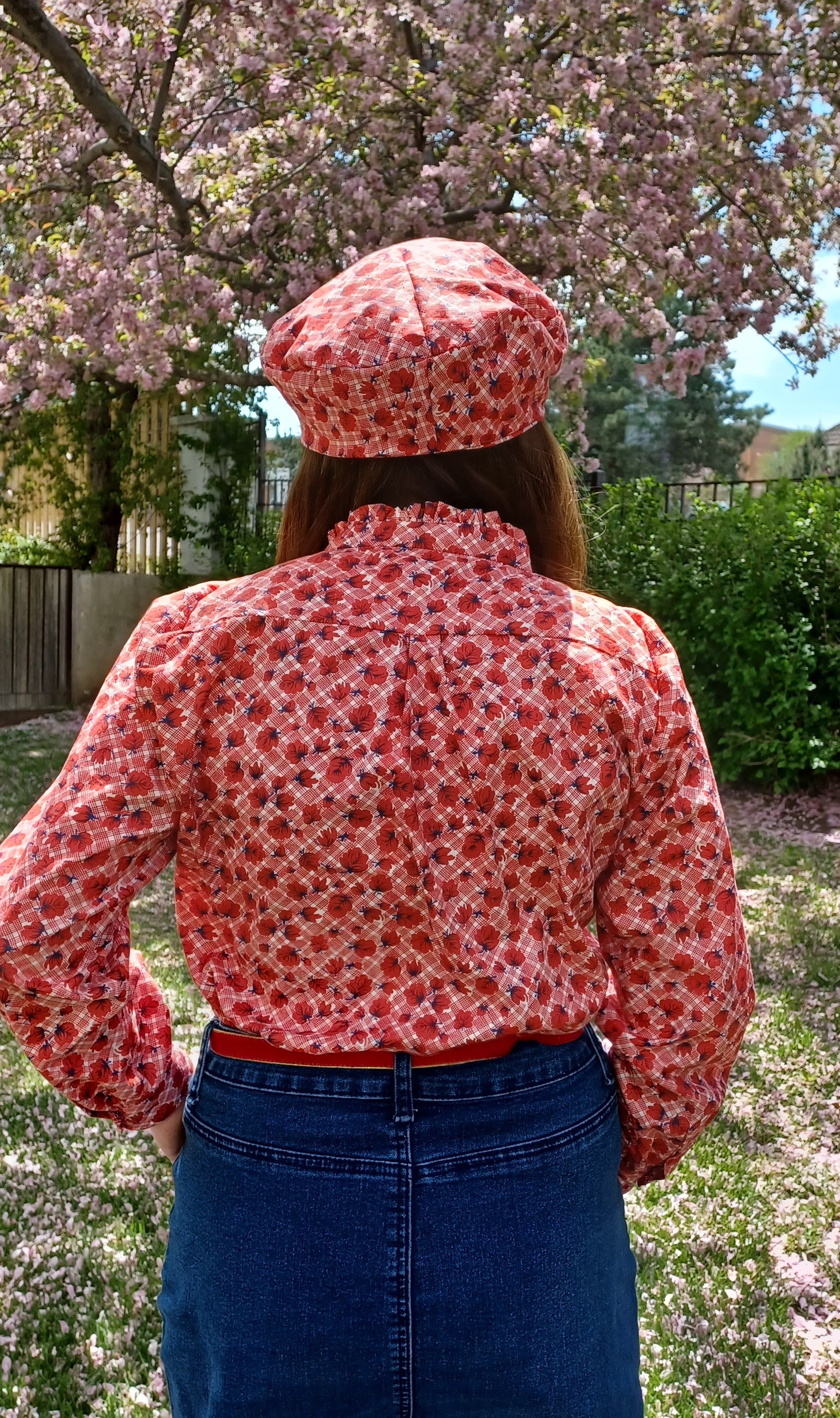 PDF sewing patterns for woven fabrics. Button down long sleeve classic top modeled by a woman with a matching beret. Floral red check fabric. Hidden placket with ruffle collar detail.