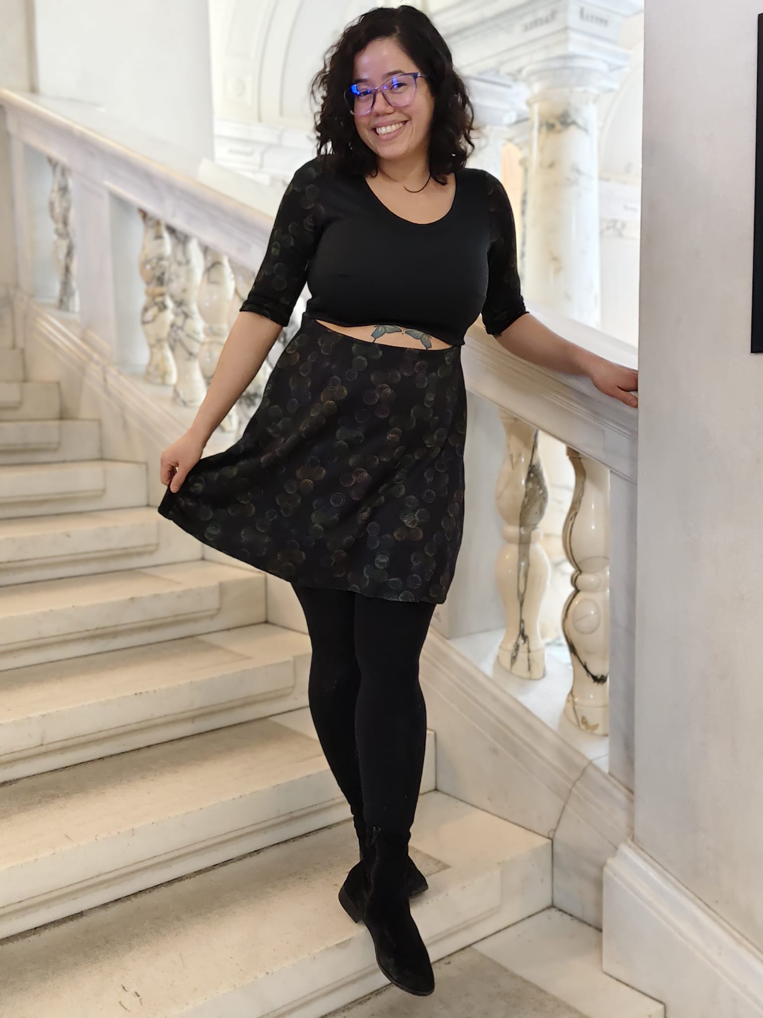 Woman in black cutout aline dress standing on a staircase
