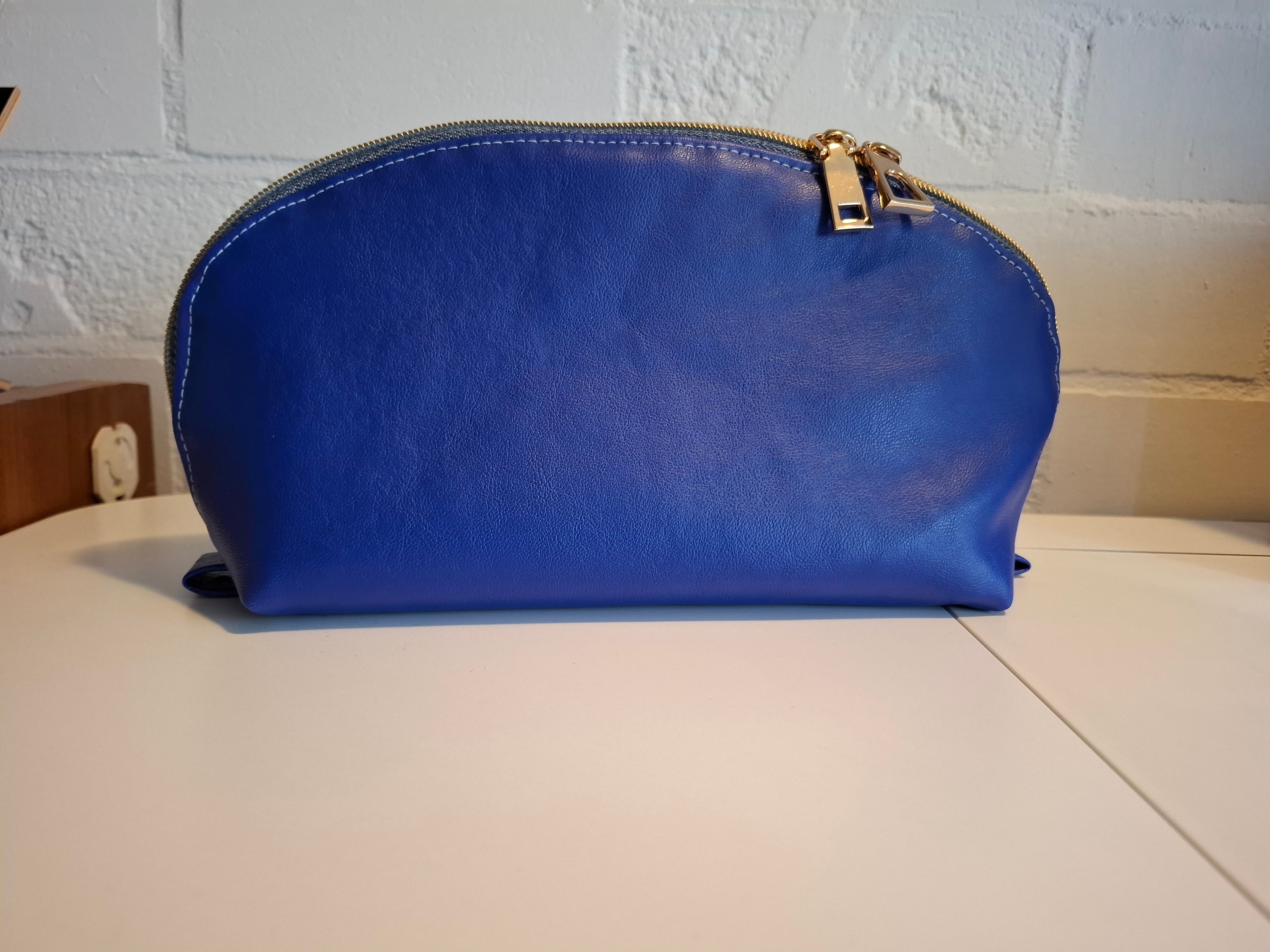 Blue cosmetic bag with a gold zipper on a white surface.