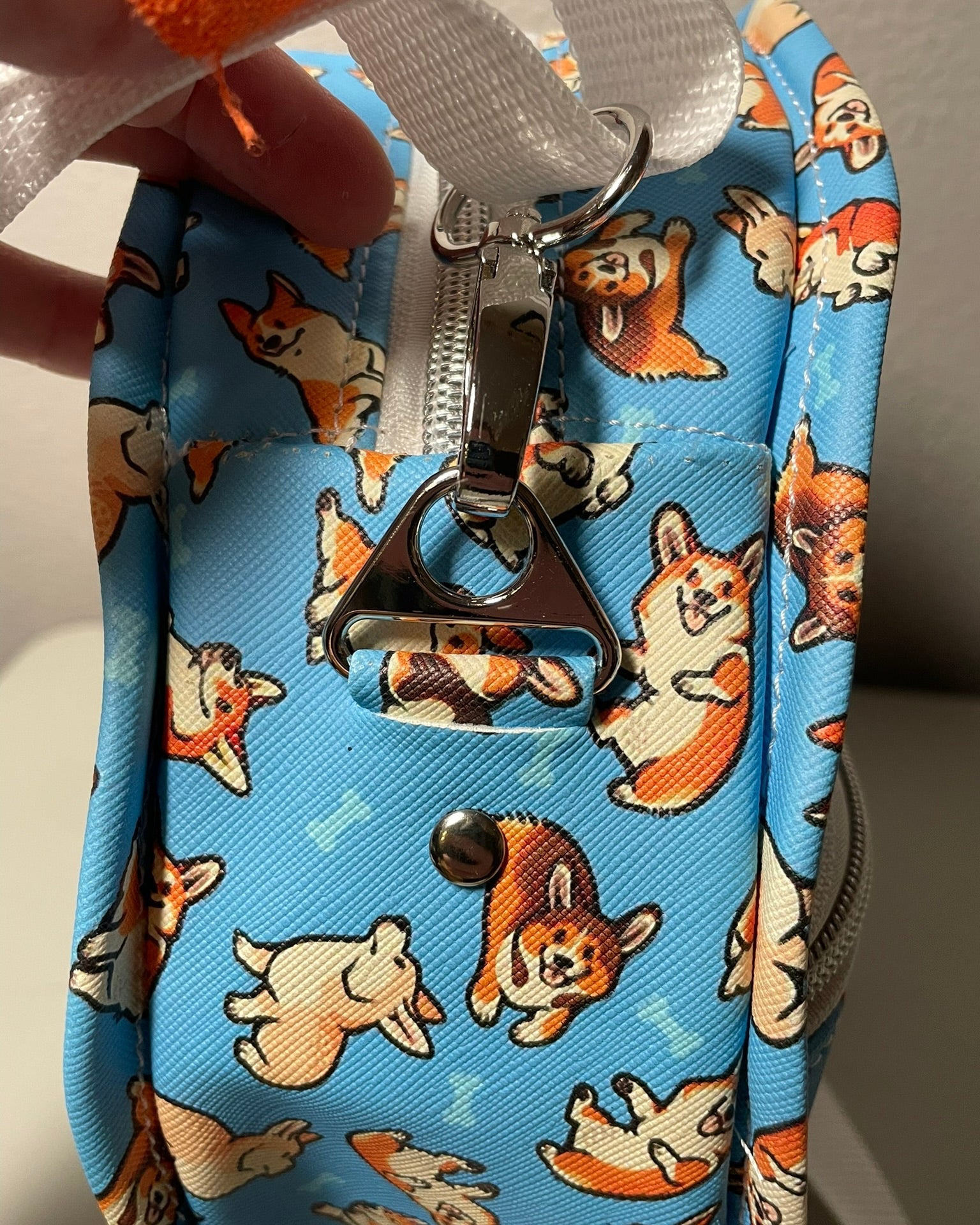 Blue DIY pouch with corgi pattern and zipper, held by a hand.