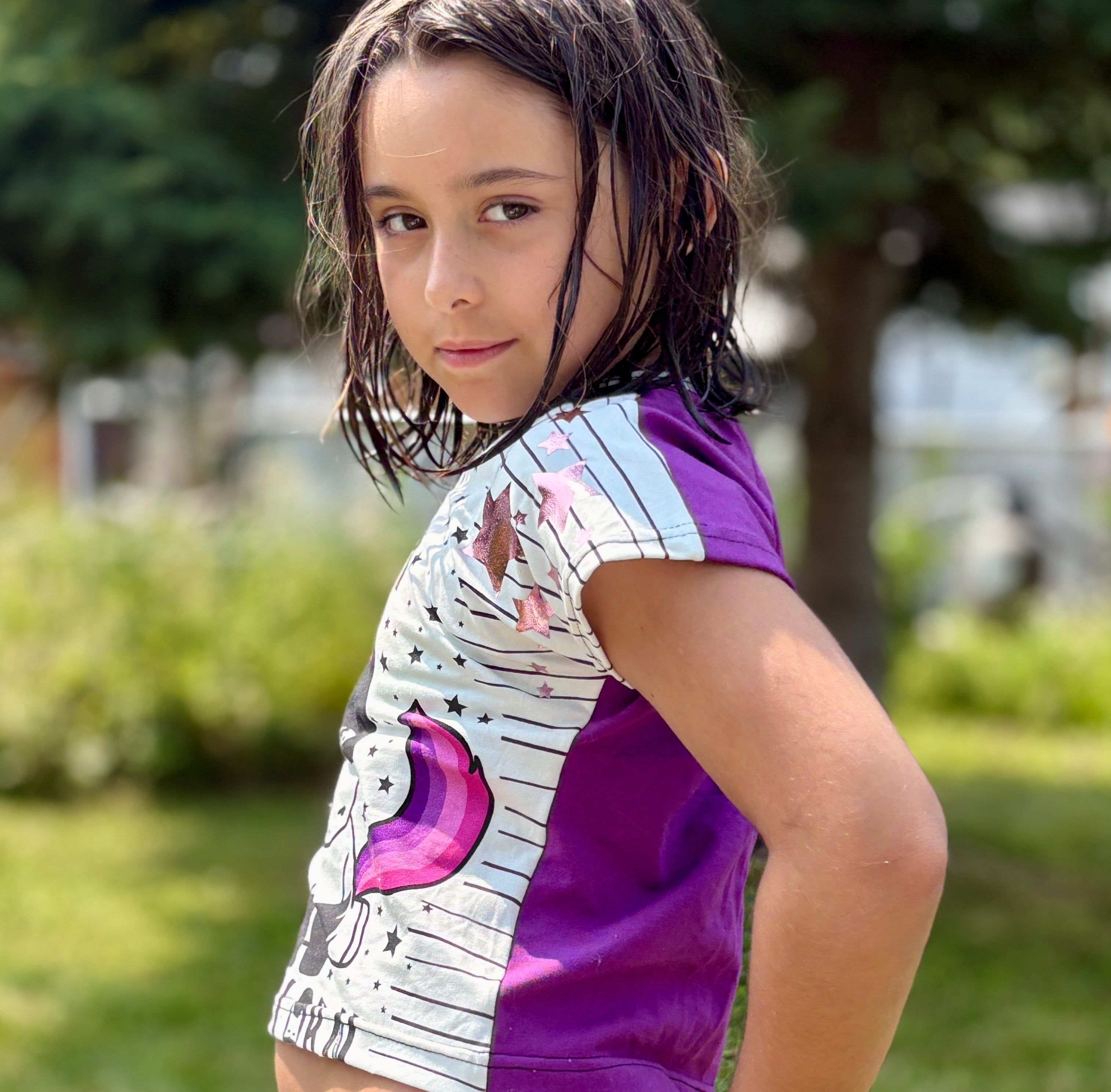 Girl modeling a crop top with print front and solid purple back dolman sewing pattern for kids by Ellie and Mac sewing patterns.