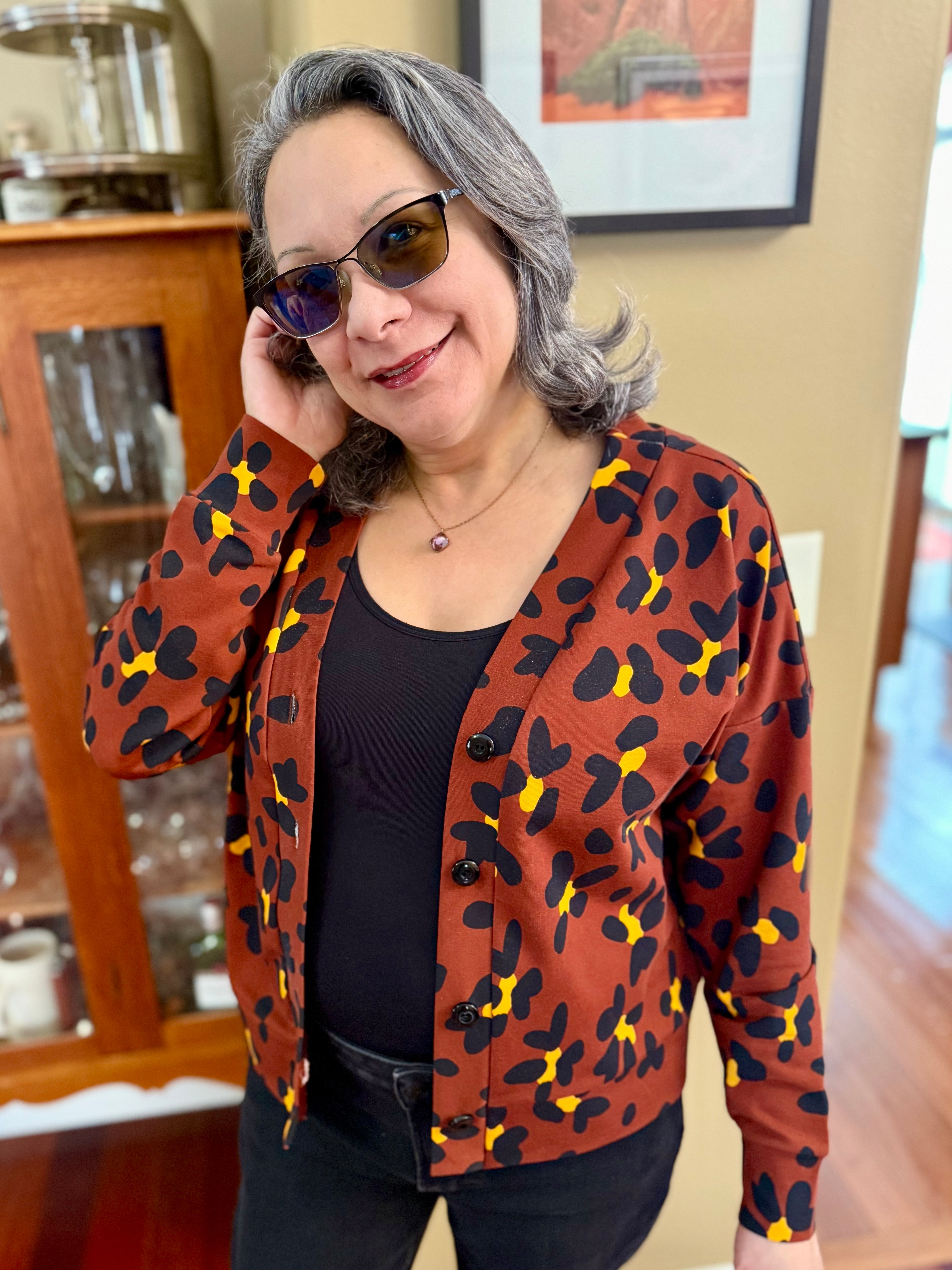 Woman wearing a handmade patterned jacket indoors with a blurred background.