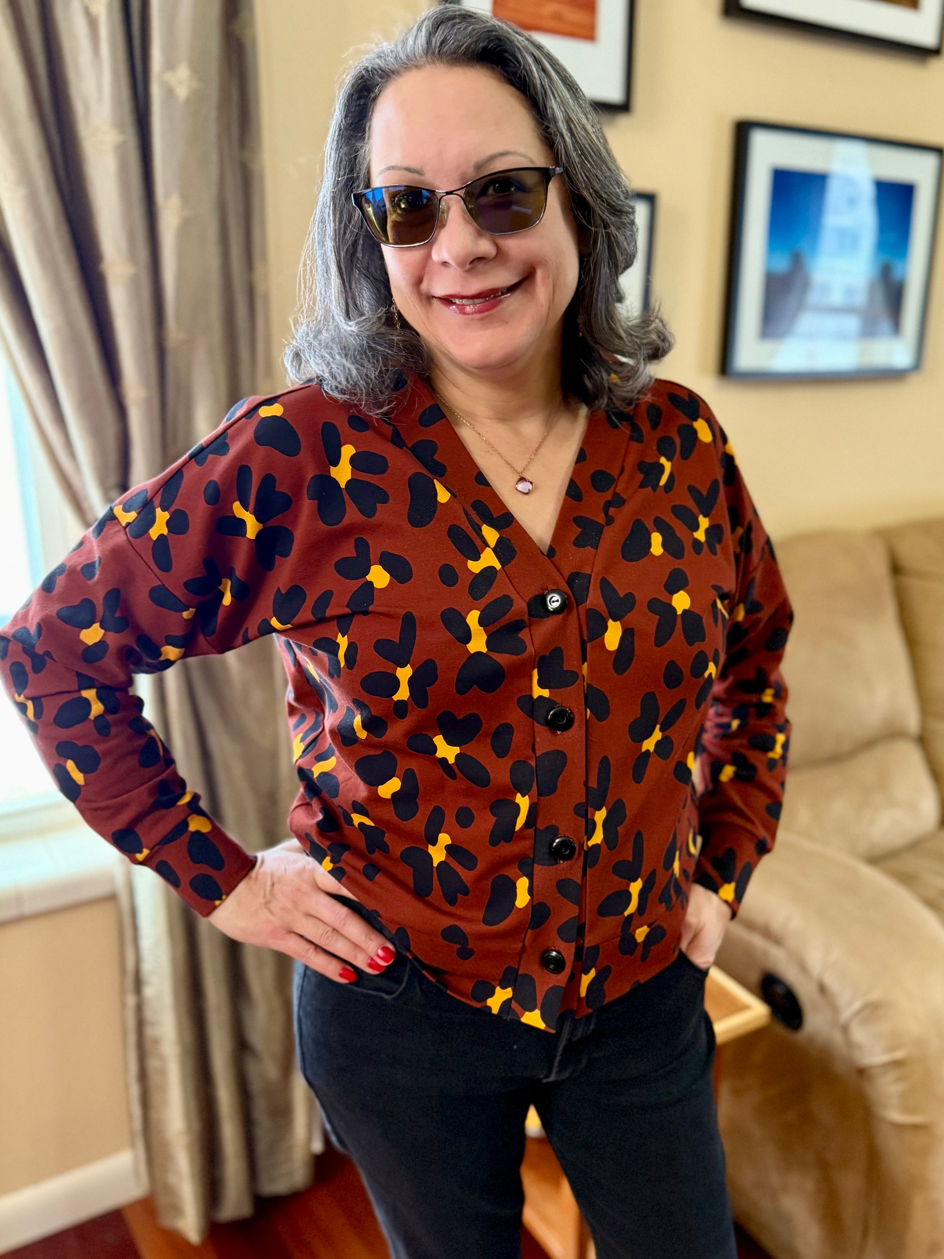 Woman wearing a brown blouse with black and yellow cheetah pattern indoors.