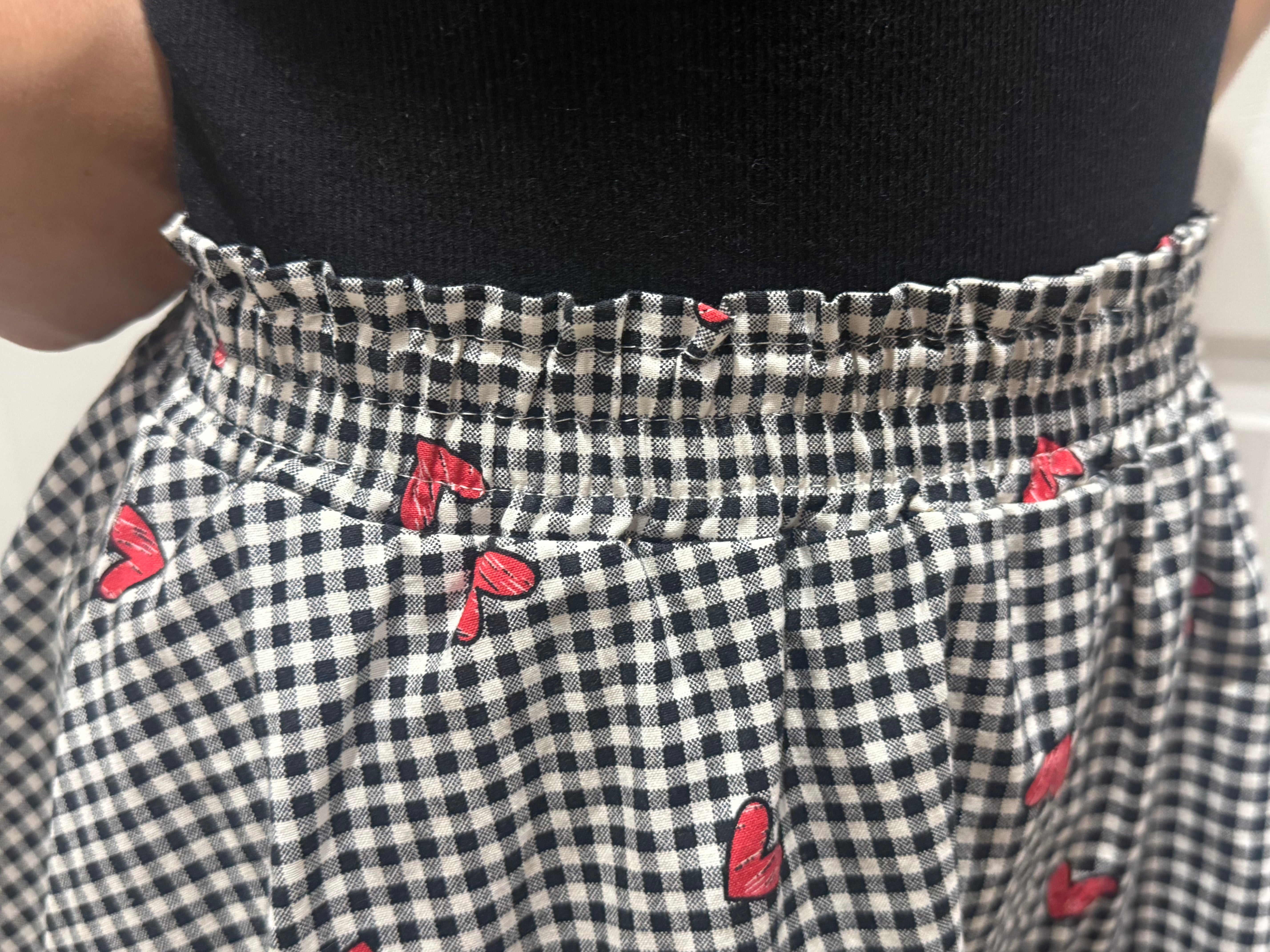 Black and white checkered skirt with red heart patterns worn by a person.
