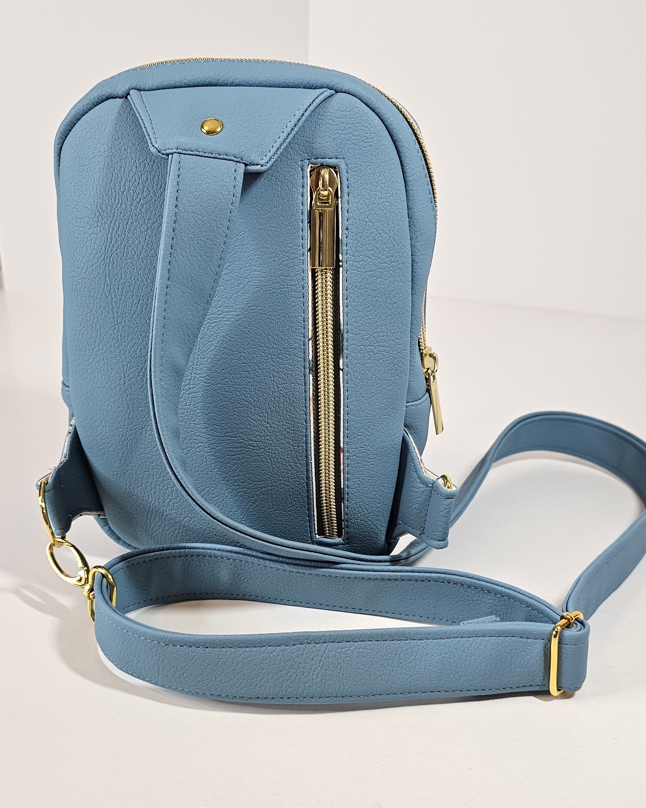 Blue handbag with gold zipper on a light gray background