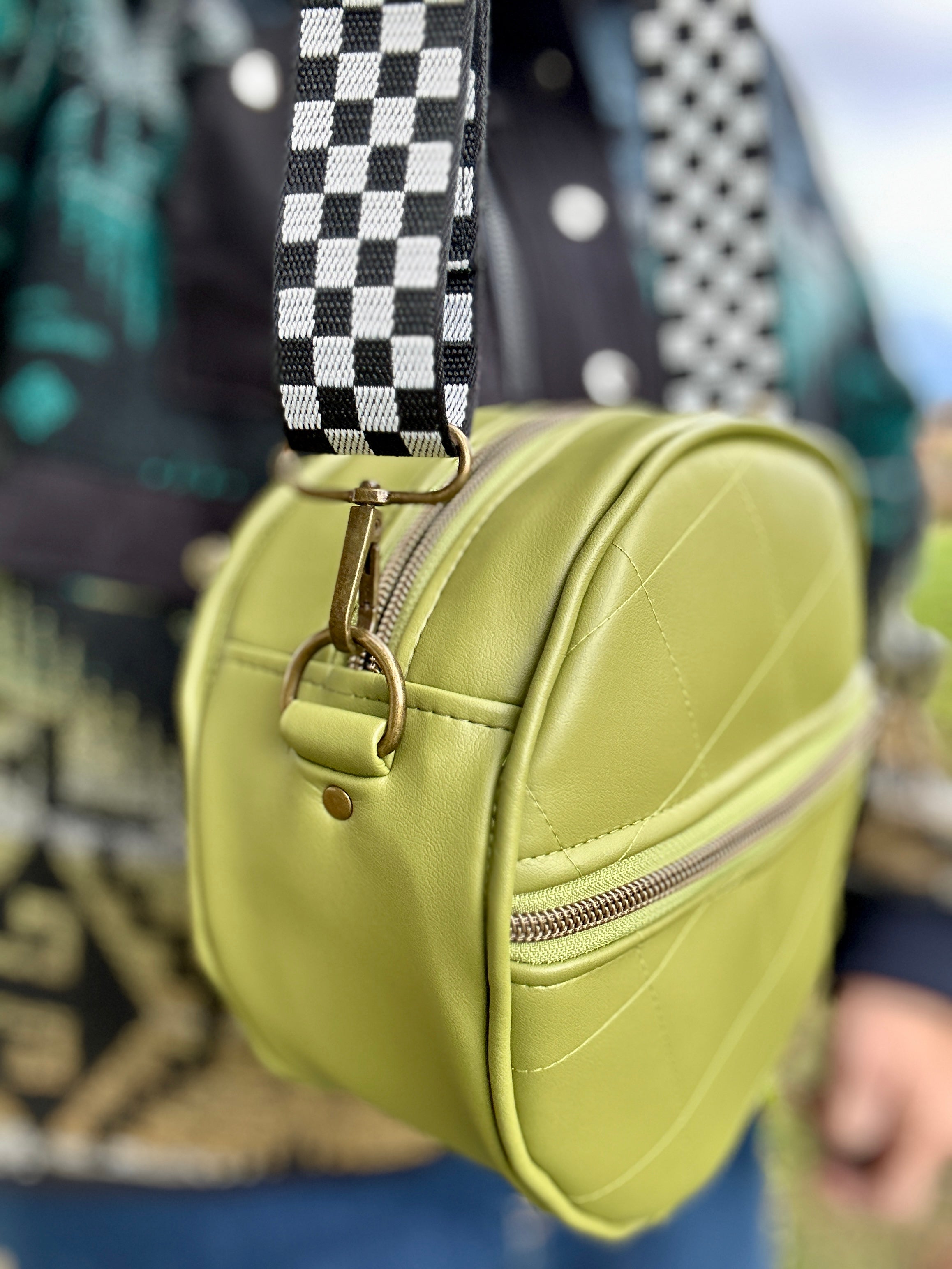 Green round bag with a checkered strap worn by a person