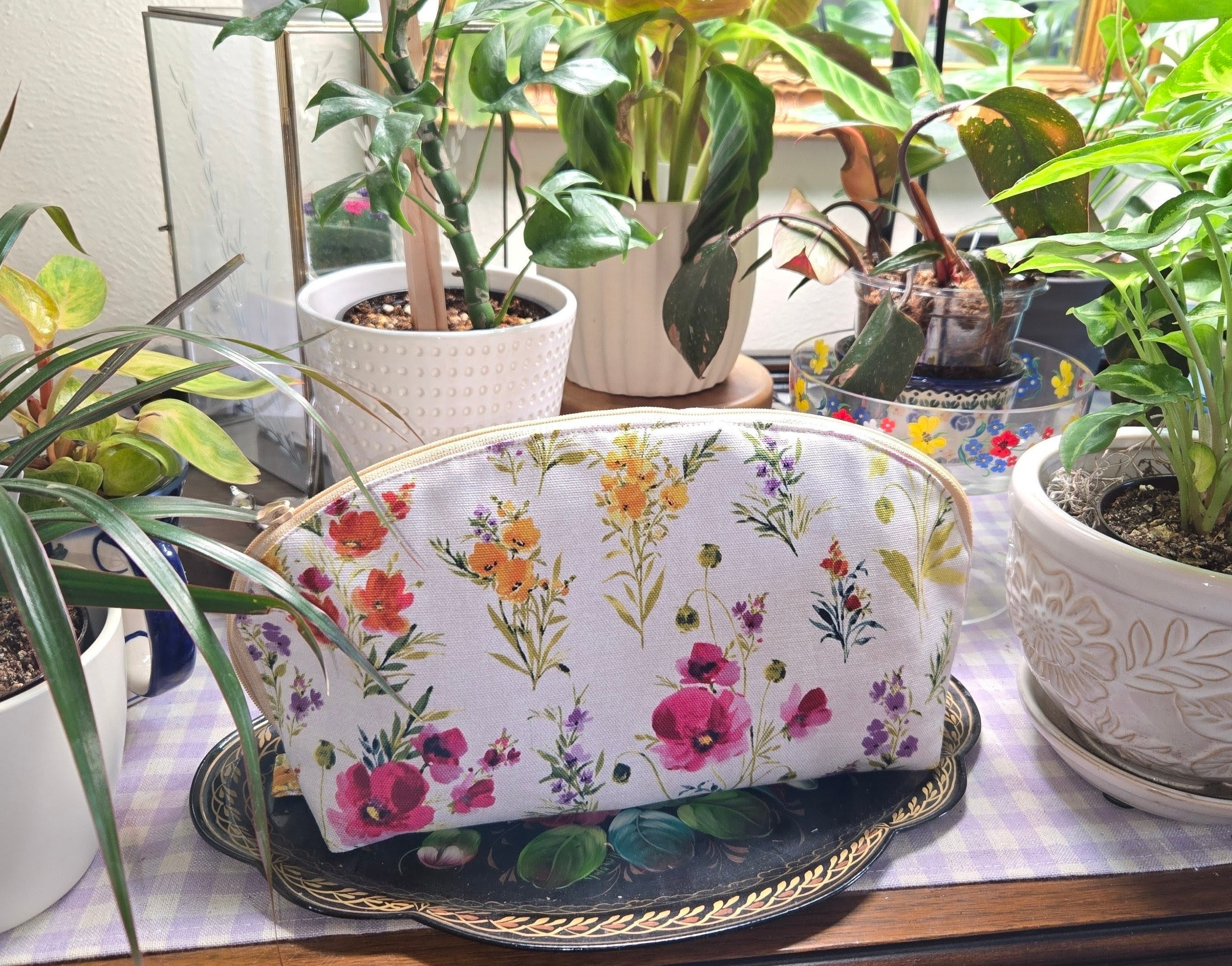 Floral-patterned pouch on a table with potted plants