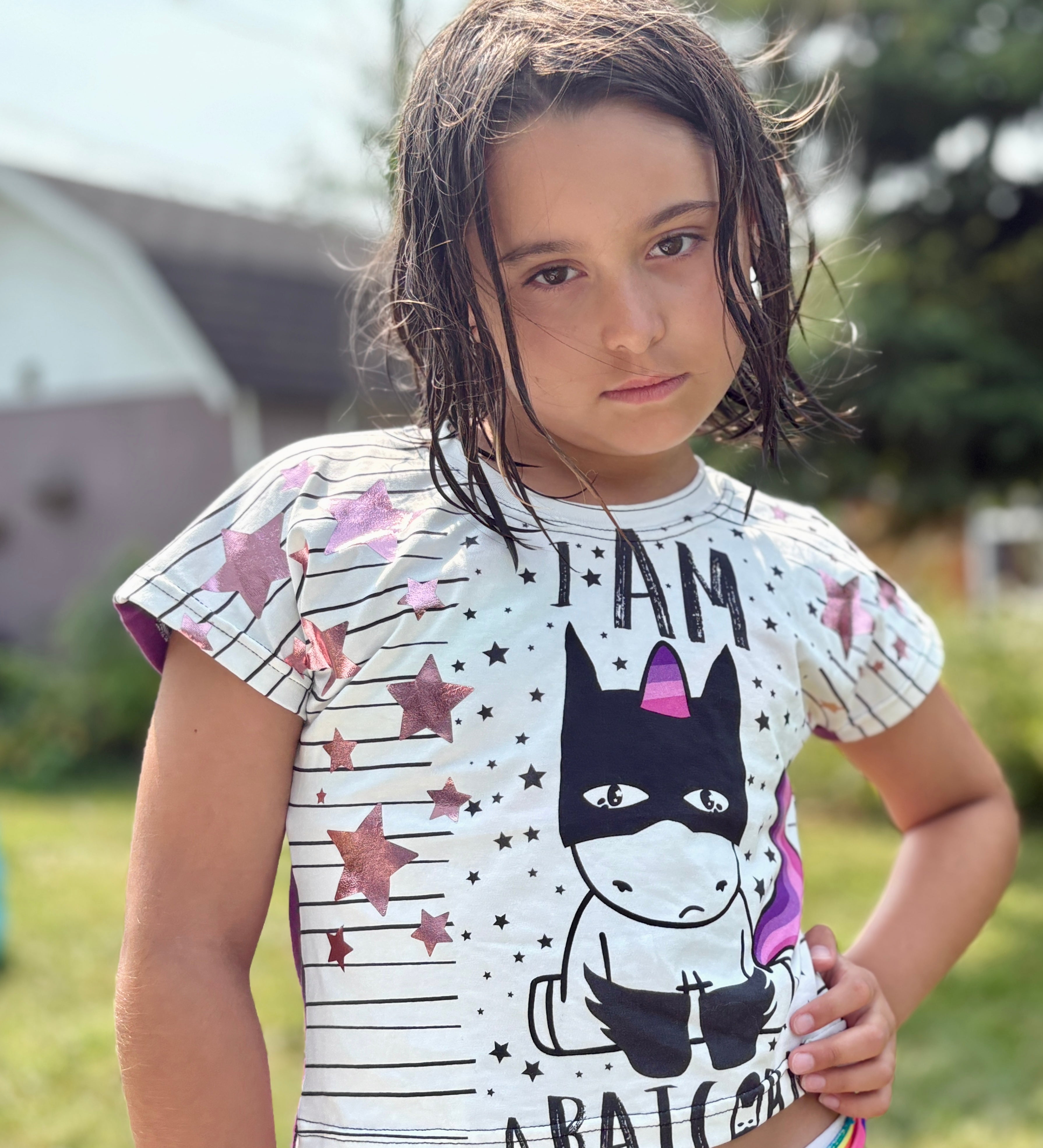 Child wearing a graphic crop top with a unicorn design outdoors.