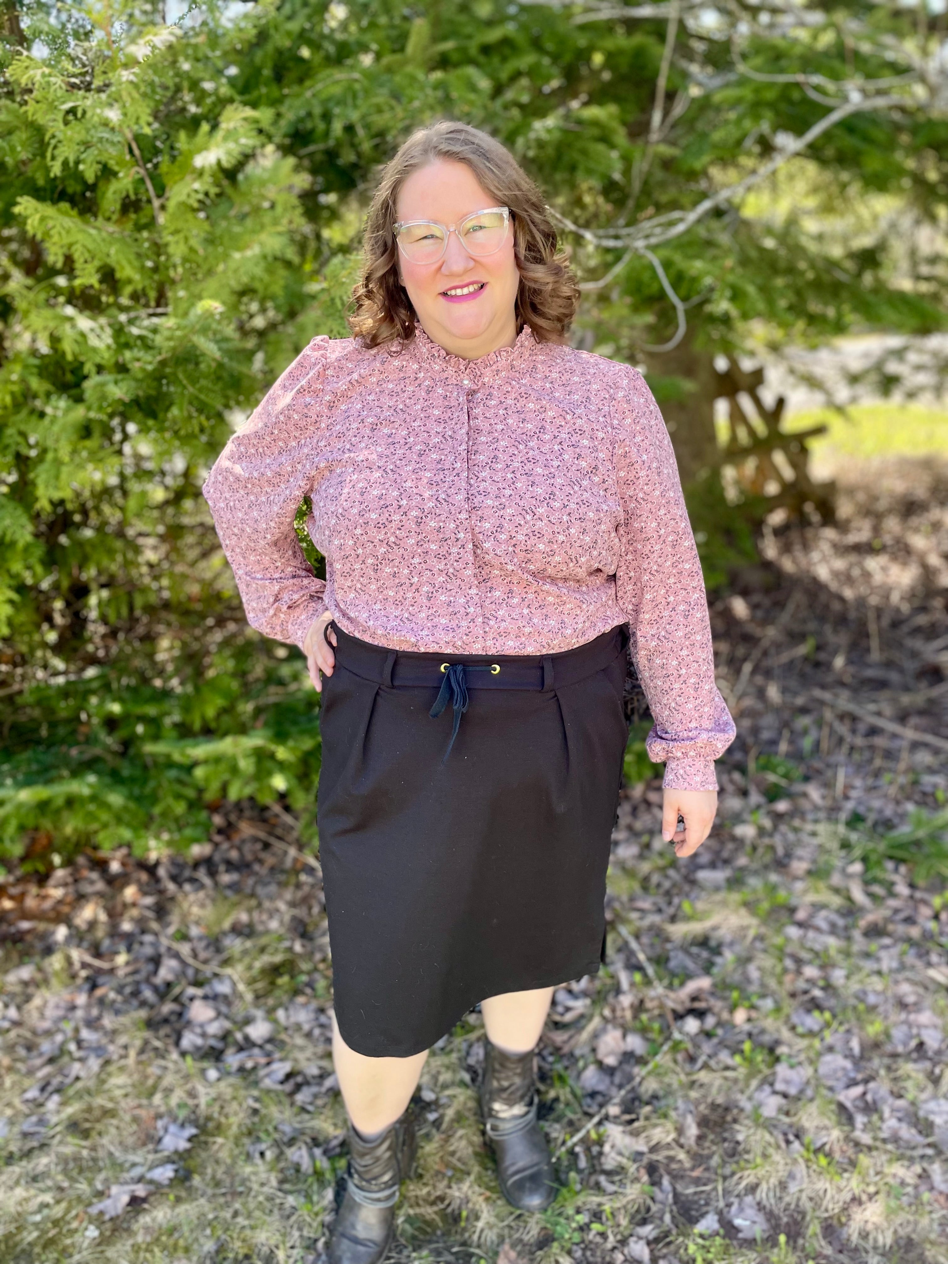 Light pink long sleeve Button Down Hidden Placket Shirt Sewing Pattern by Ellie and Mac sewing patterns. This pattern is modeled on a woman with a black skirt and the floral woven button down top. PDF pattern.