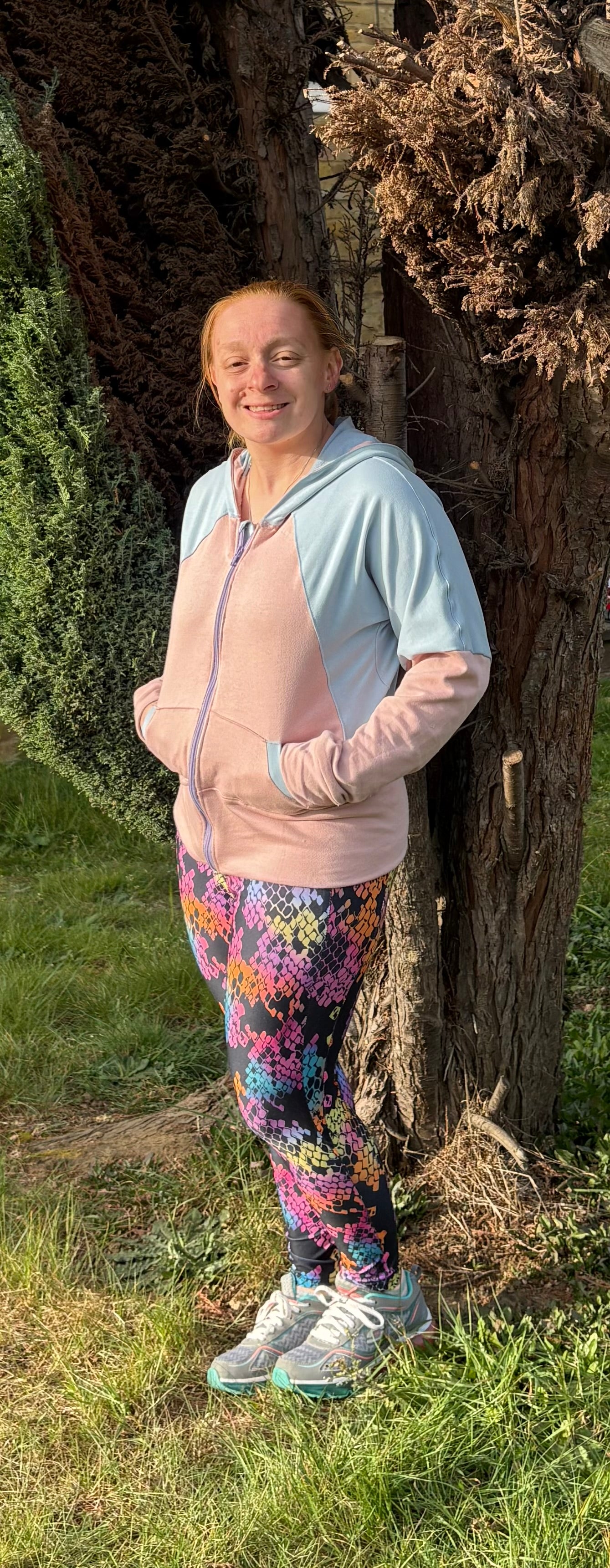 Woman outside modeling a light pink and light blue raglan bomber jacket with zip closure, kangaroo pocket detail, and cuffs. Projector file sewing.