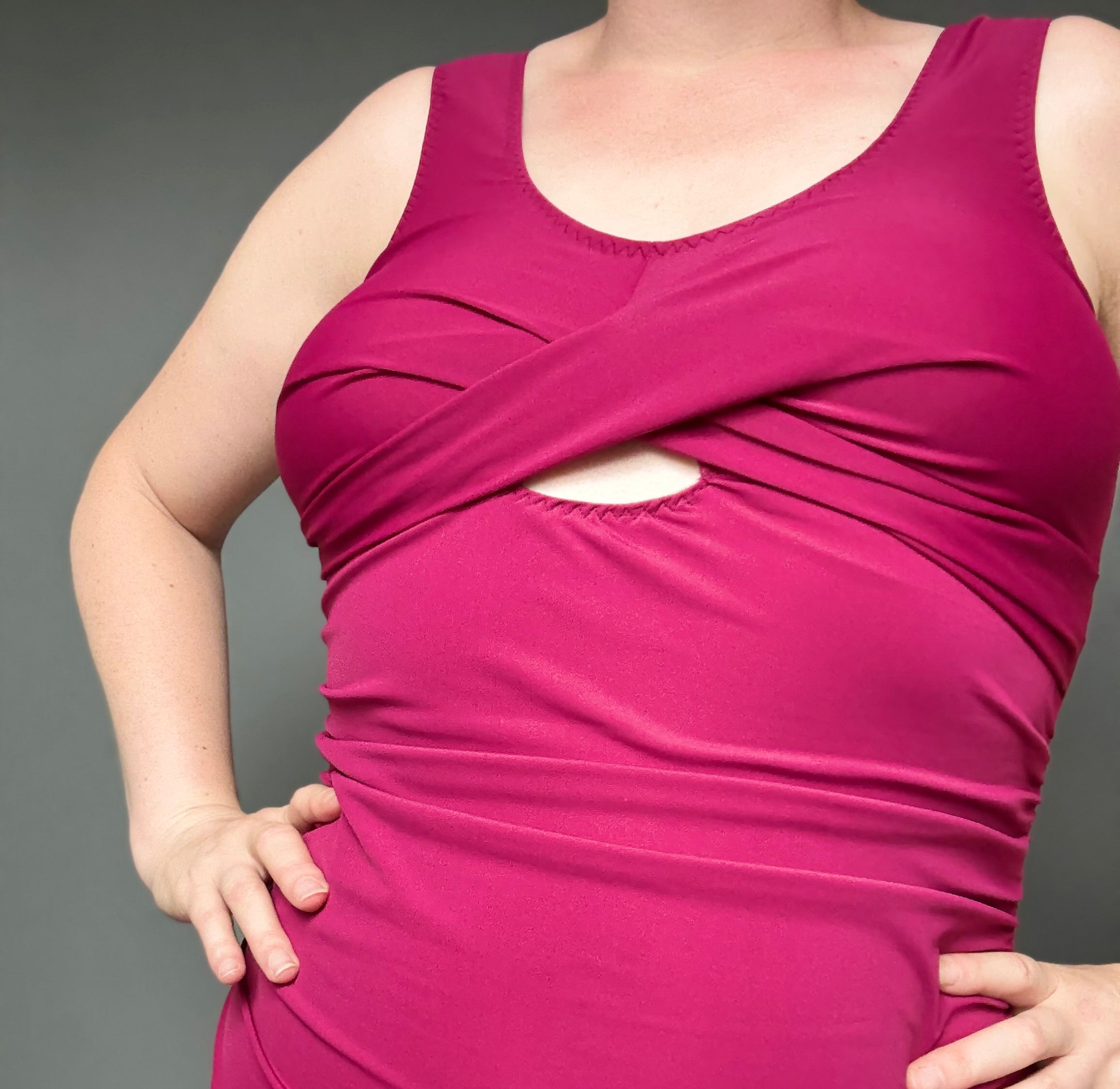 Person wearing a pink sleeveless swimsuit against a gray background