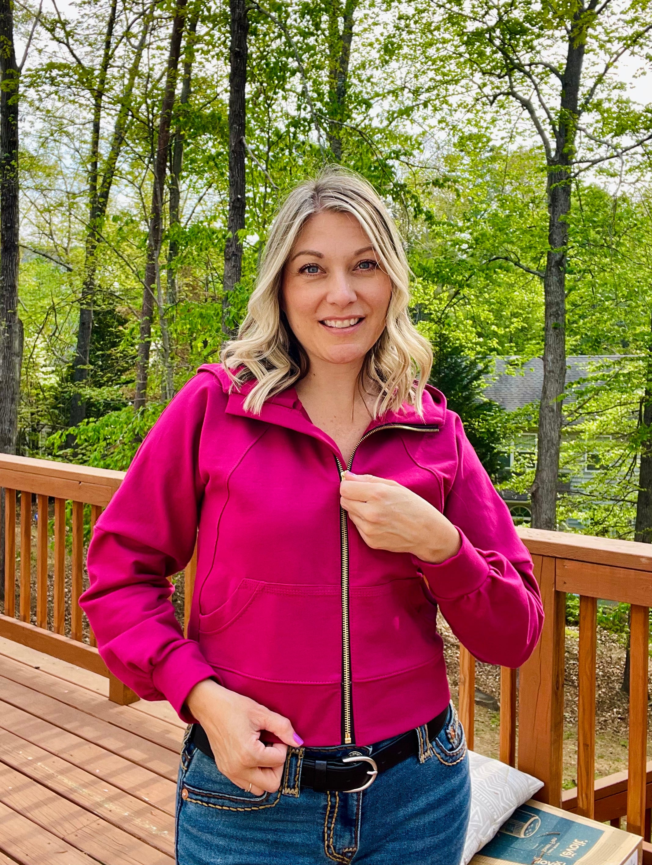 woman wearing a Bright raspberry pink heavy french terry fabric from knitfabric.com sewn into a hooded athletic jacket with zip closure. bishop raglan dolman sleeves. Cropped version.