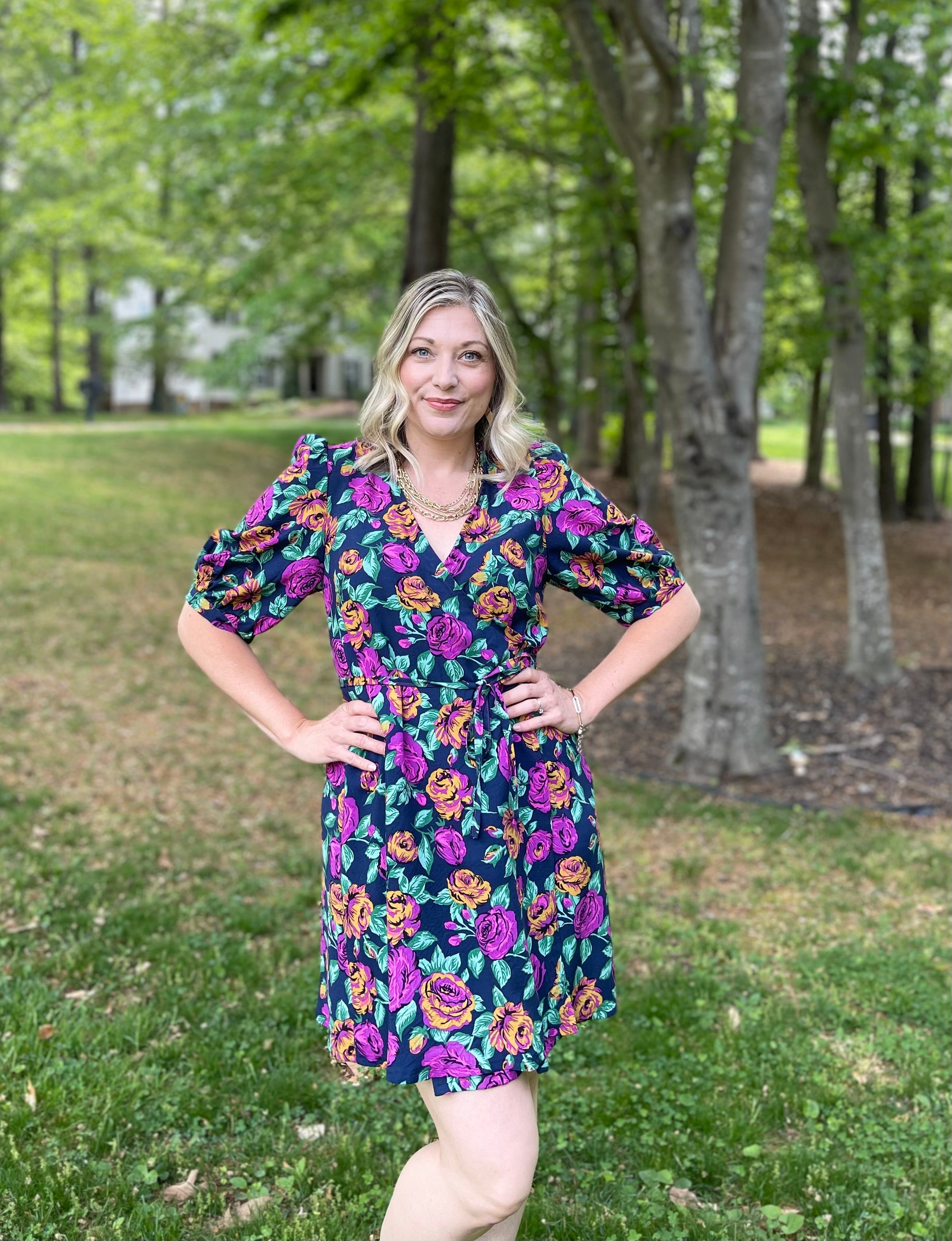 Woven floral wrap dress with elbow puff sleeves and thin ties. Stunning right purple and orange flowers pop on the navy vicose fabric. Leonie Wrap Top and Dress Pattern.