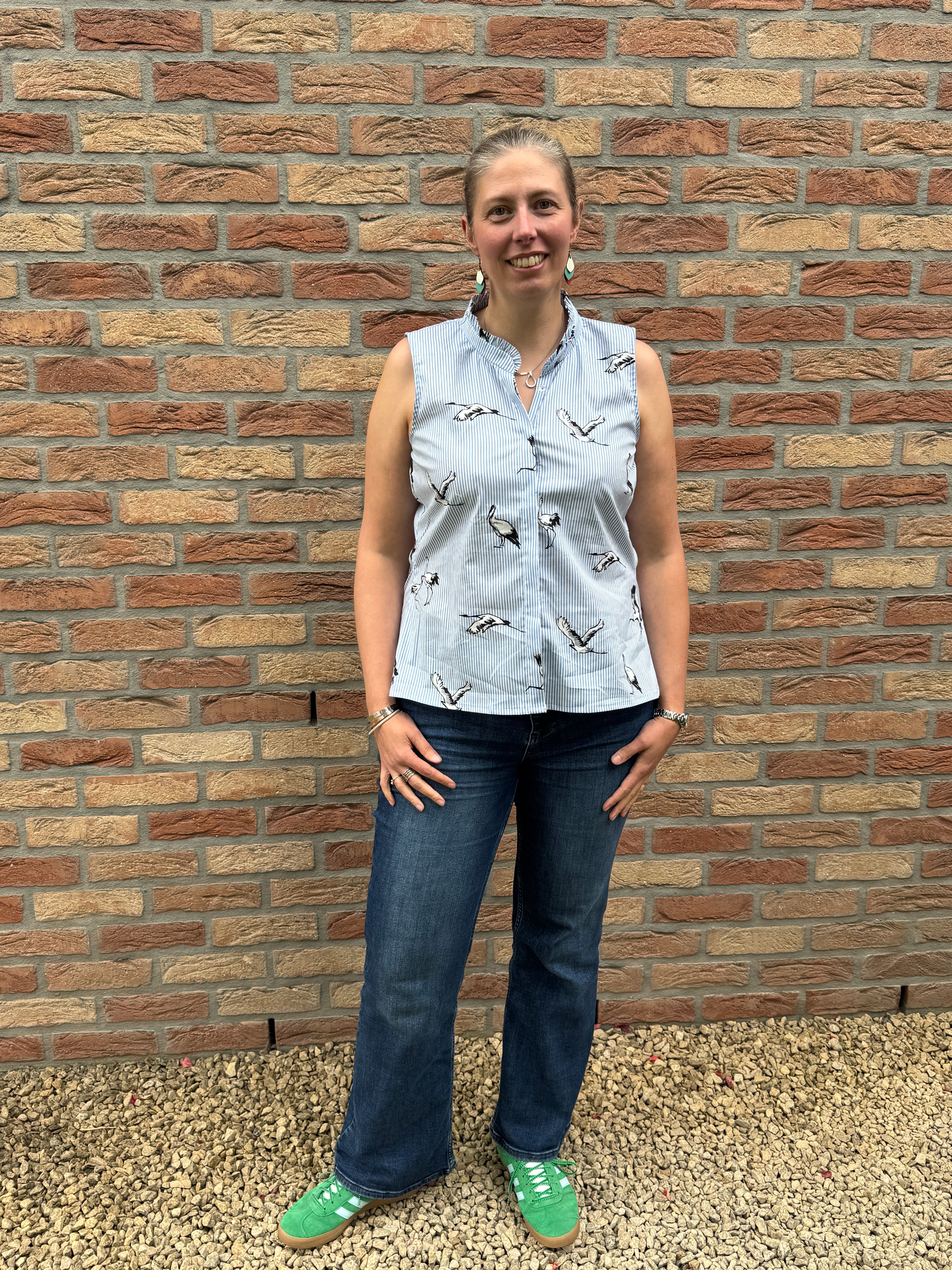 PDF sewing patterns for woven fabrics. Button down sleeveless classic top modeled by a woman. Striped crane print fabric. Hidden placket with ruffle collar detail.