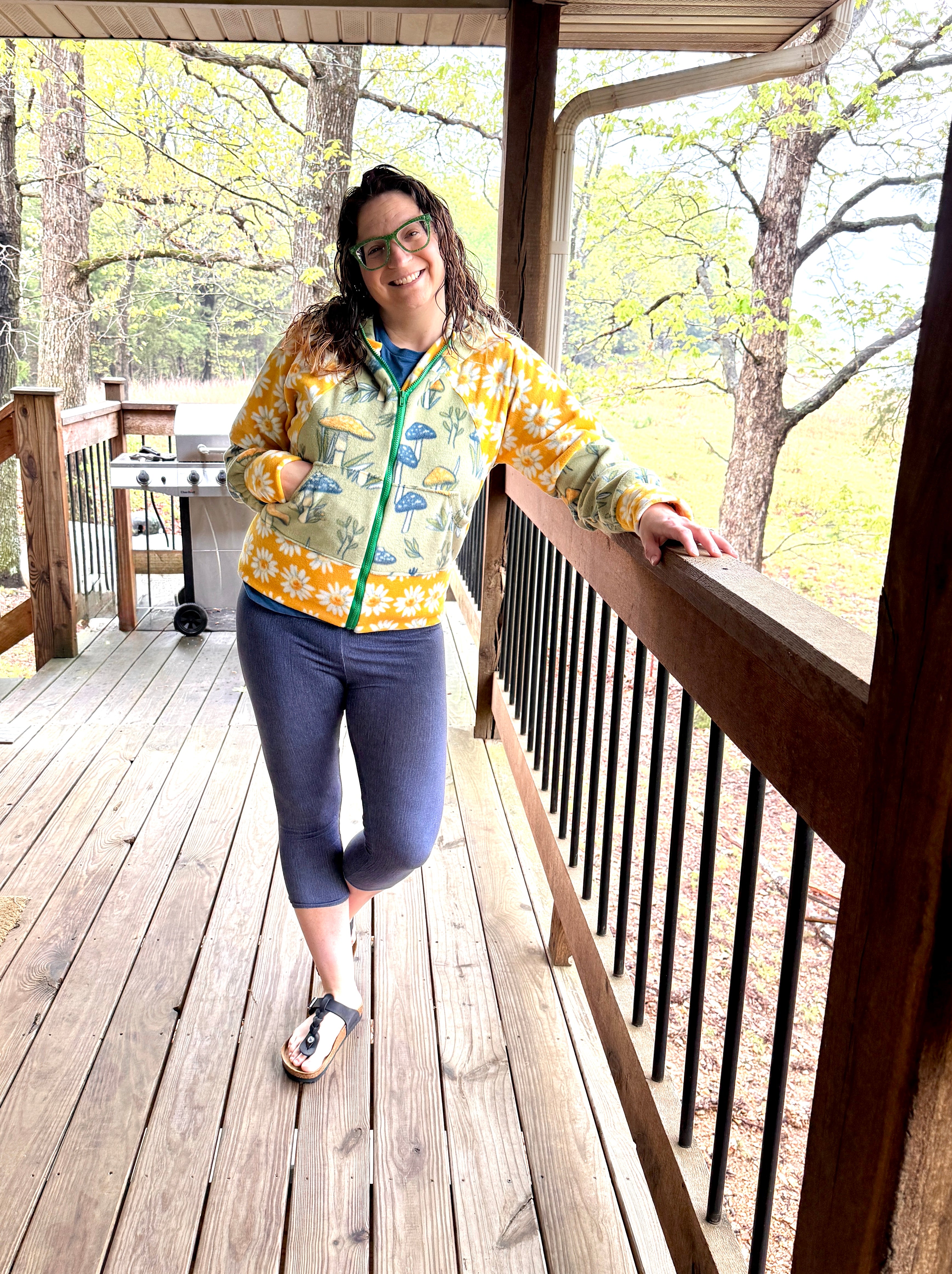Woman on a deck modeling a bright color-block athletic hooded jacket with zip closure, kangaroo pocket detail, and cuffs. Easy pdf sewing pattern.
