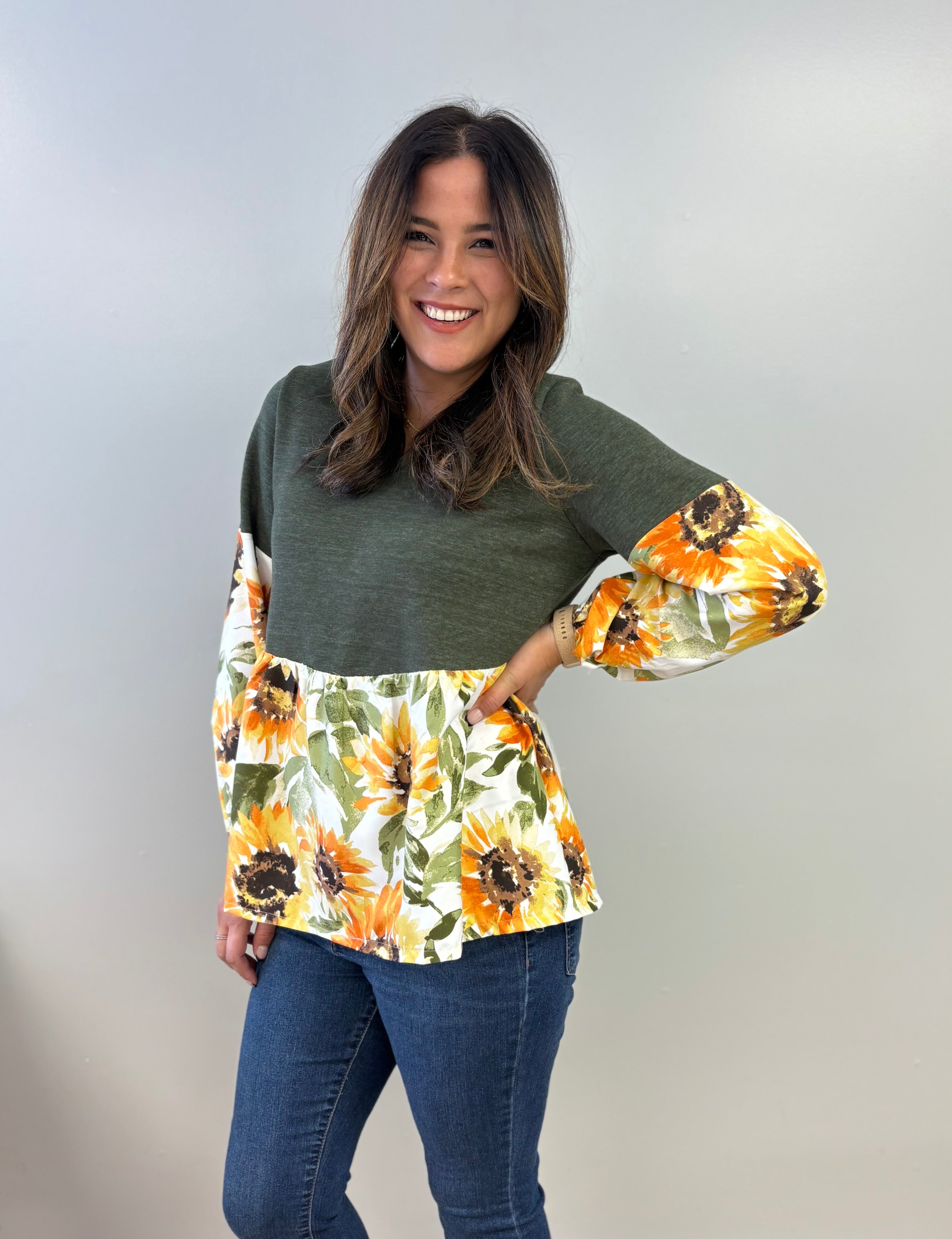 Woman wearing a green peasant top with floral bishop sleeves against a plain background. Easy sewing pattern for fall.