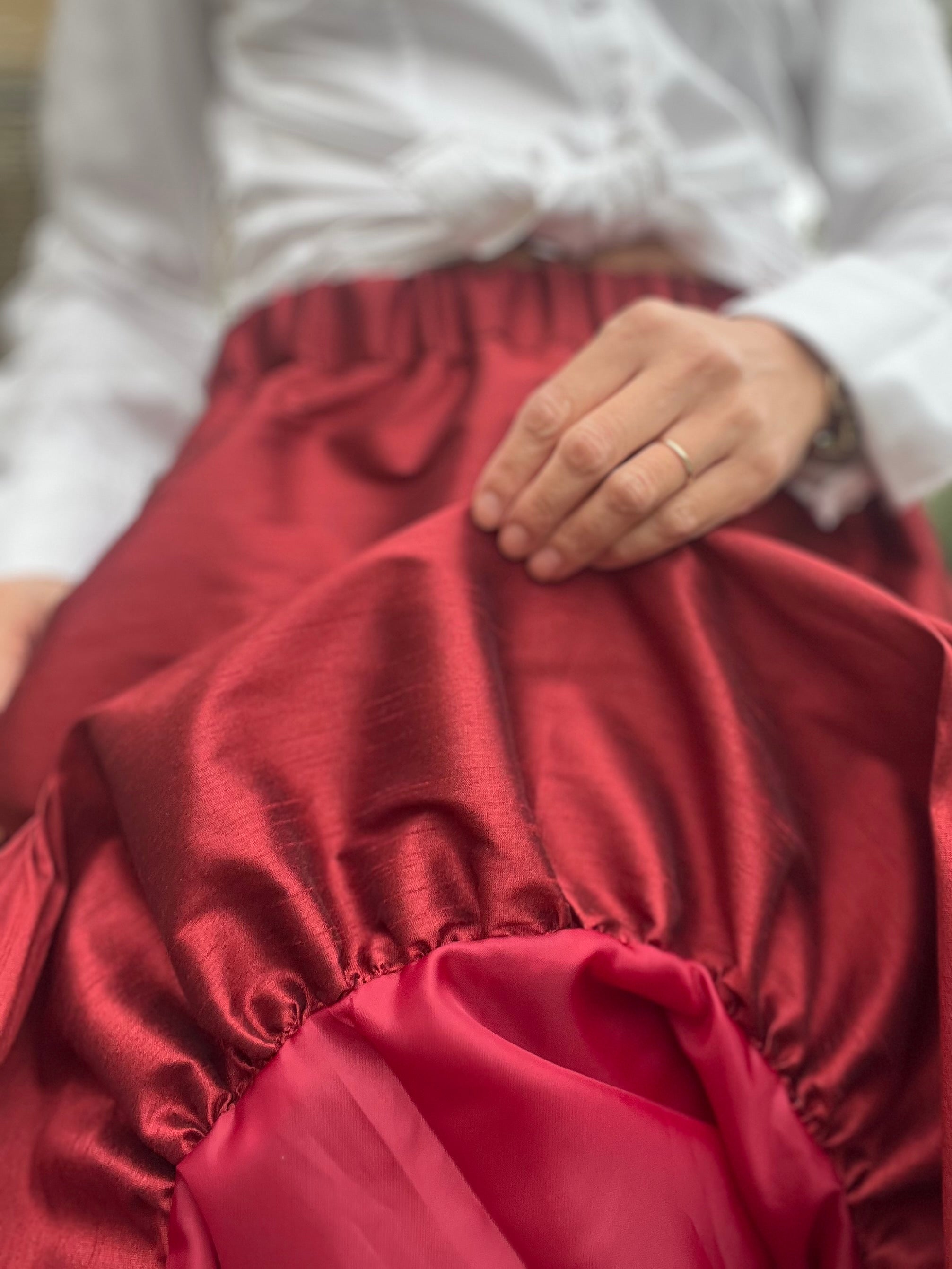 Close-up of red taffeta fabric with a blurred background. Shows the Bubble outer sewn to the under skirt.