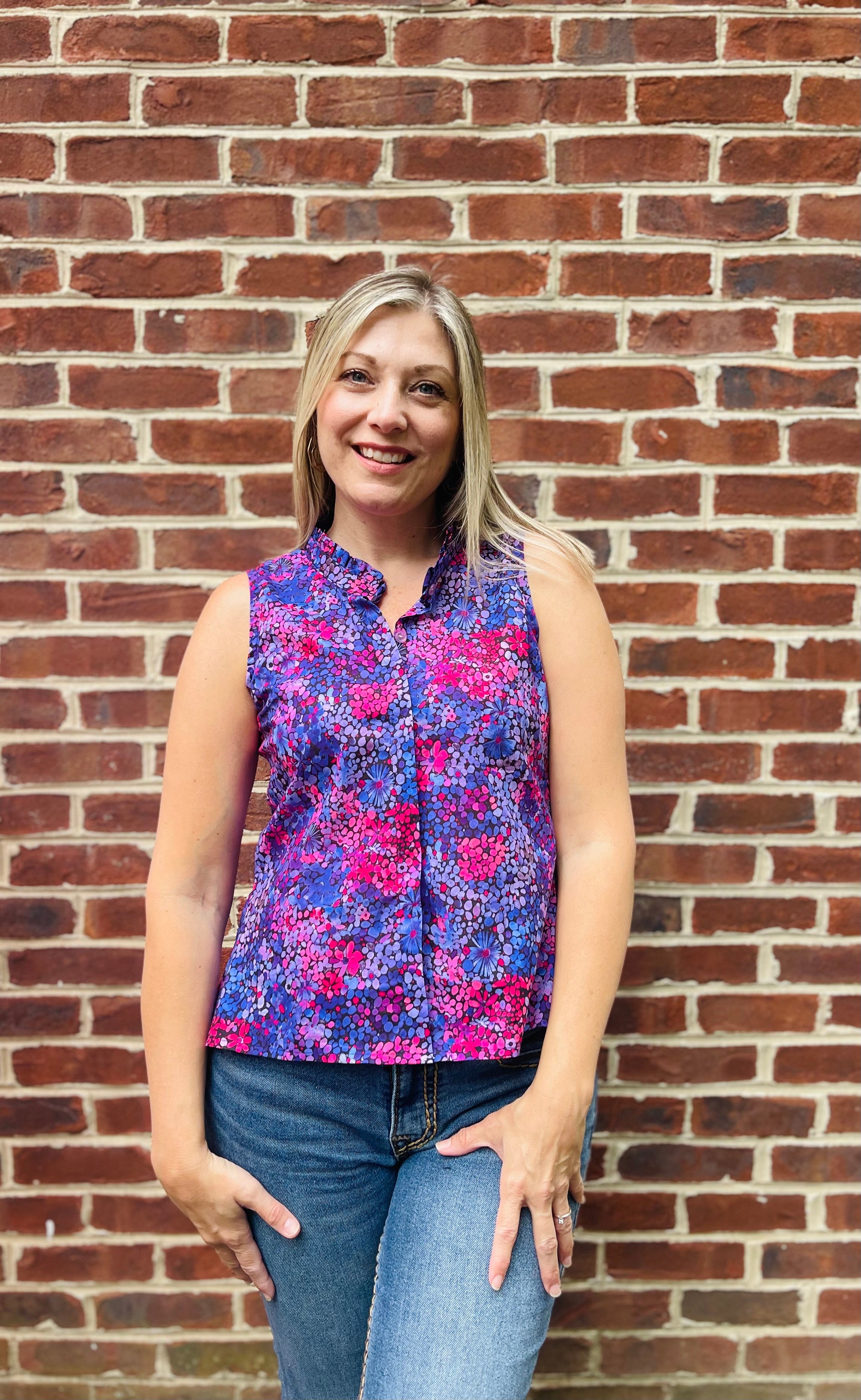 PDF sewing patterns for woven fabrics. Button down sleeveless top modeled by a blond woman. Floral voile fabric. Hidden placket with ruffle collar detail.