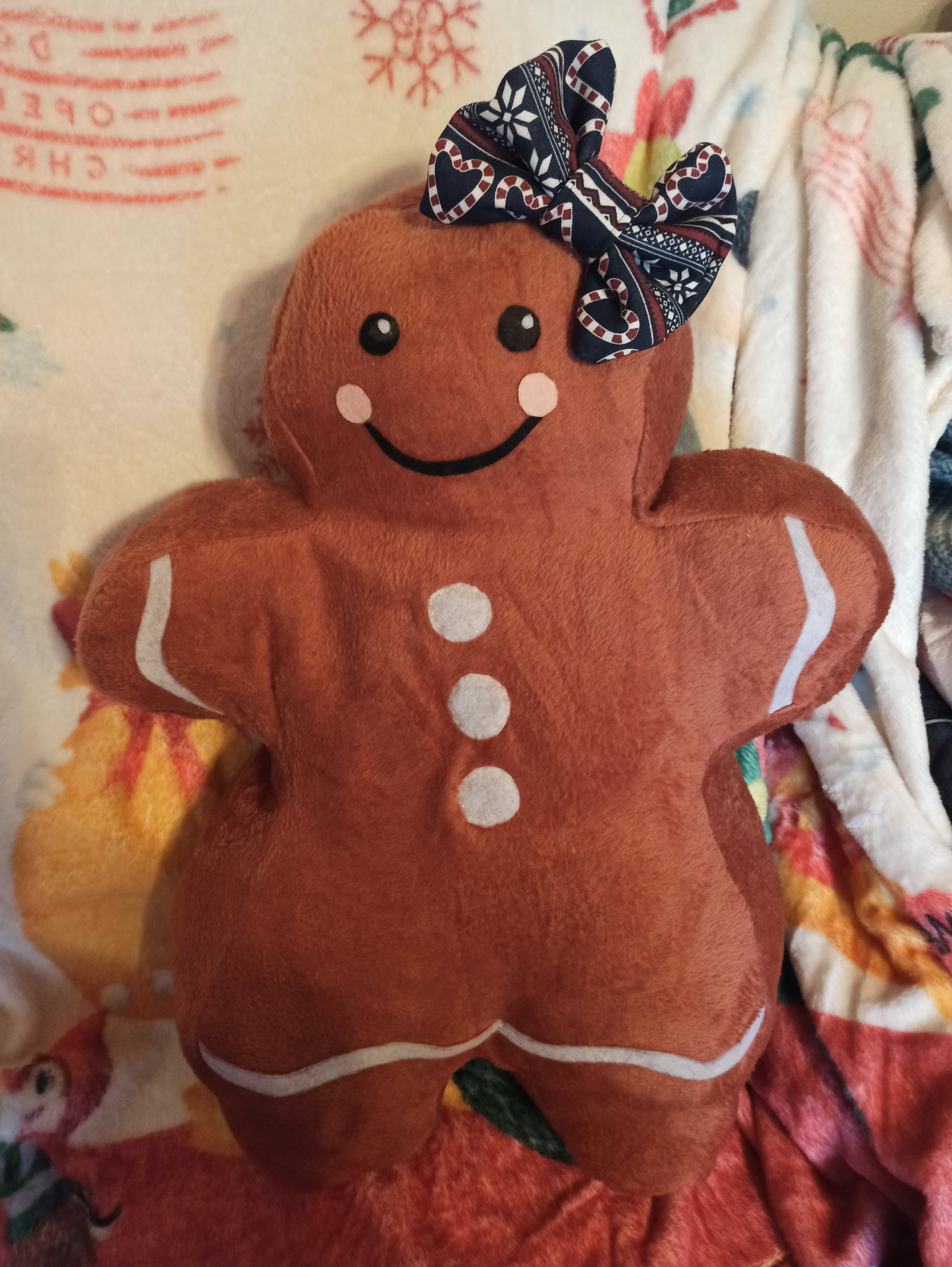 Plush gingerbread girl toy with a bow on a colorful blanket