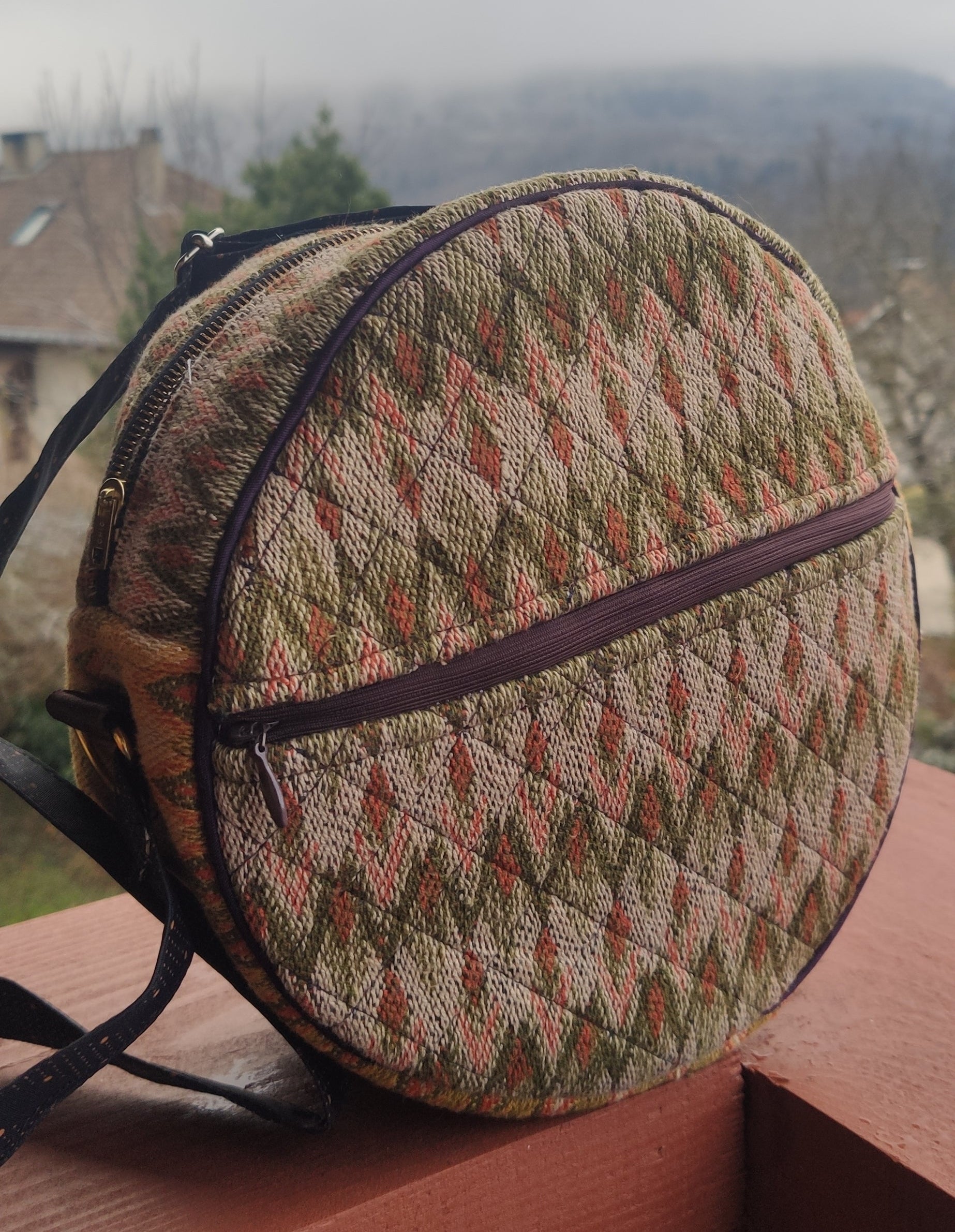 handmade round woven bag with a patterned design on a wooden surface.