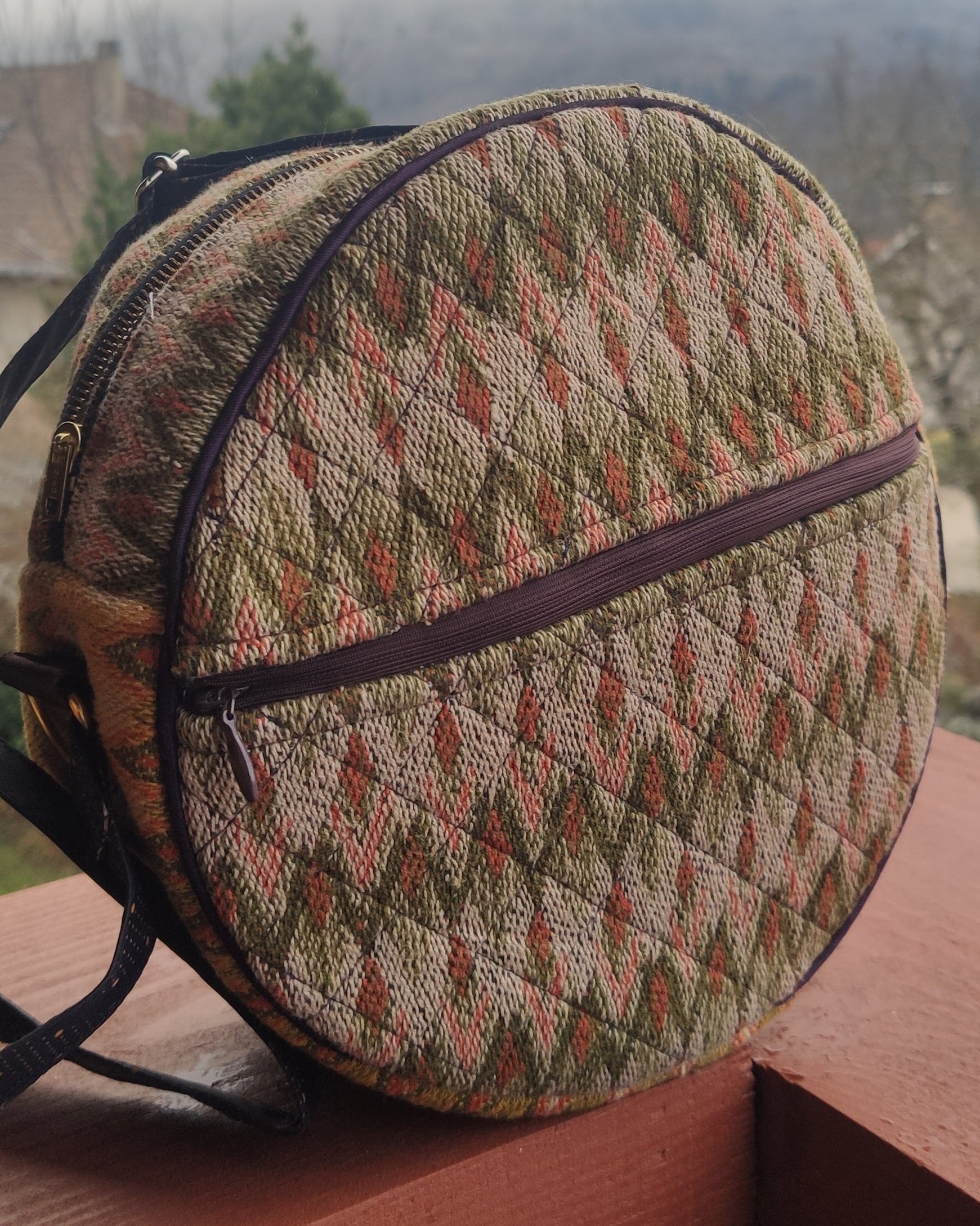 handmade round woven bag with a patterned design on a wooden surface.