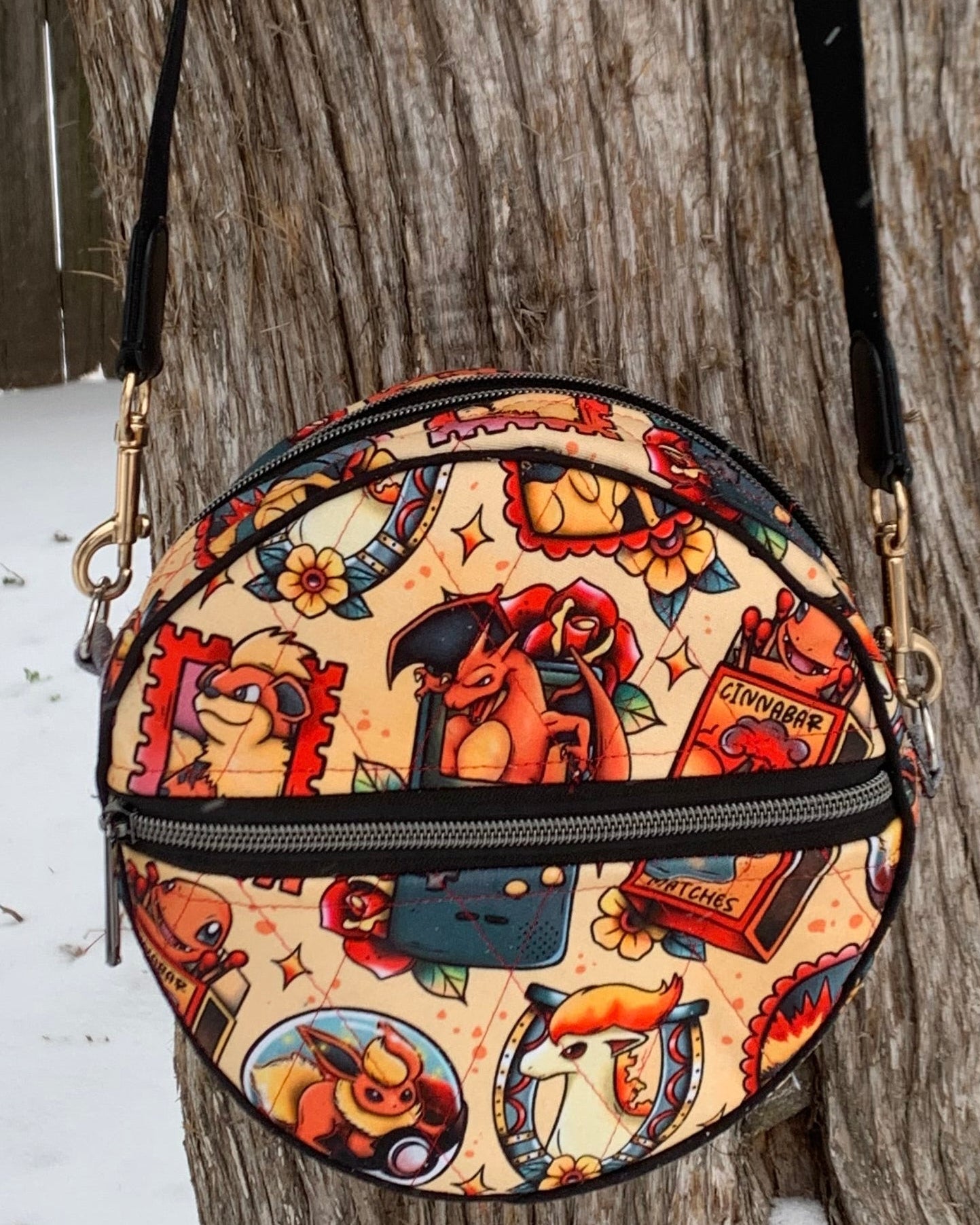character round vinyl bag with zipper and adjustable strap. Can be worn crossbody.