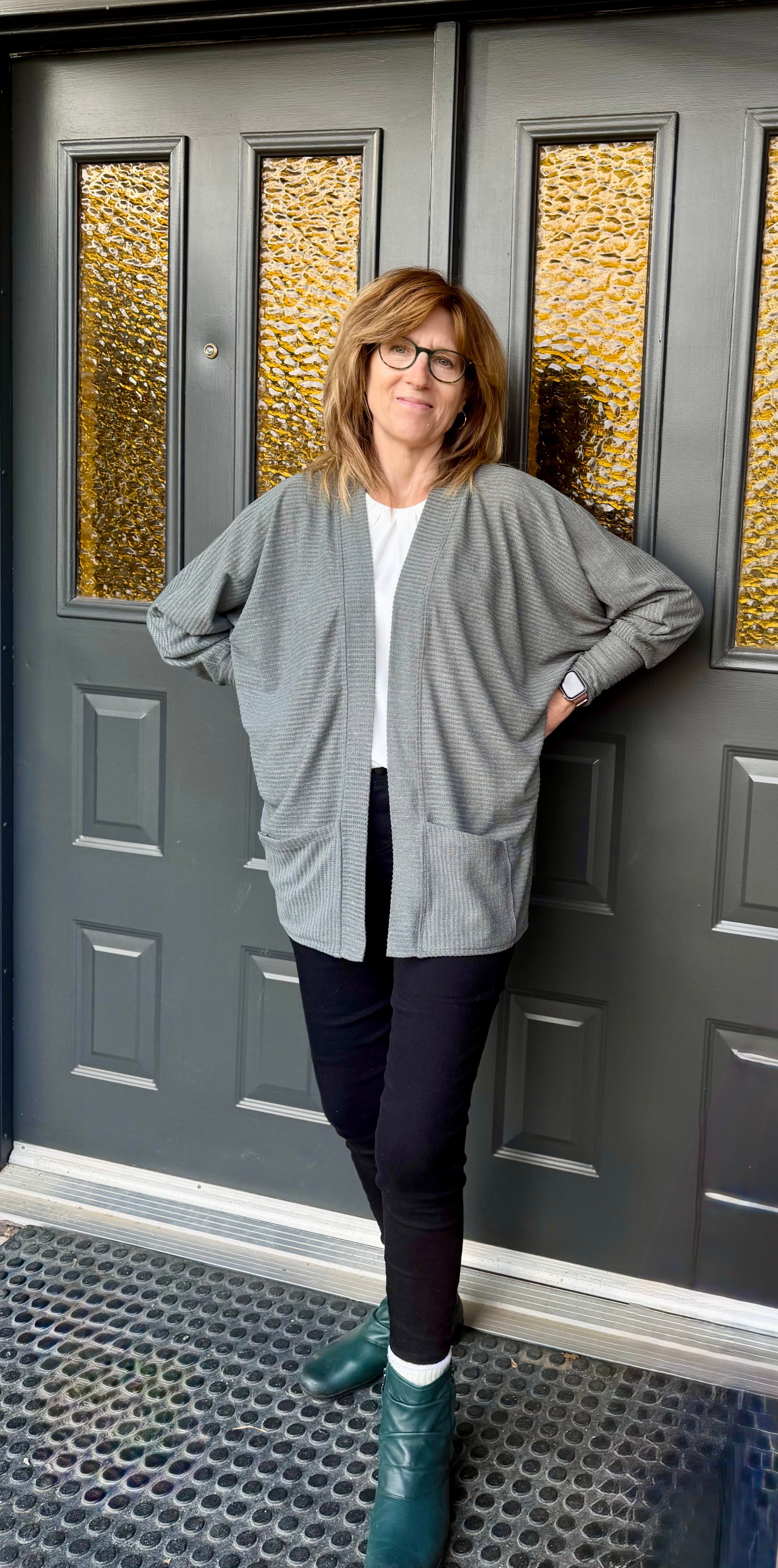 Woman modeling the Celeste Batwing Cardigan PDF sewing pattern in mid-thigh length with pockets.