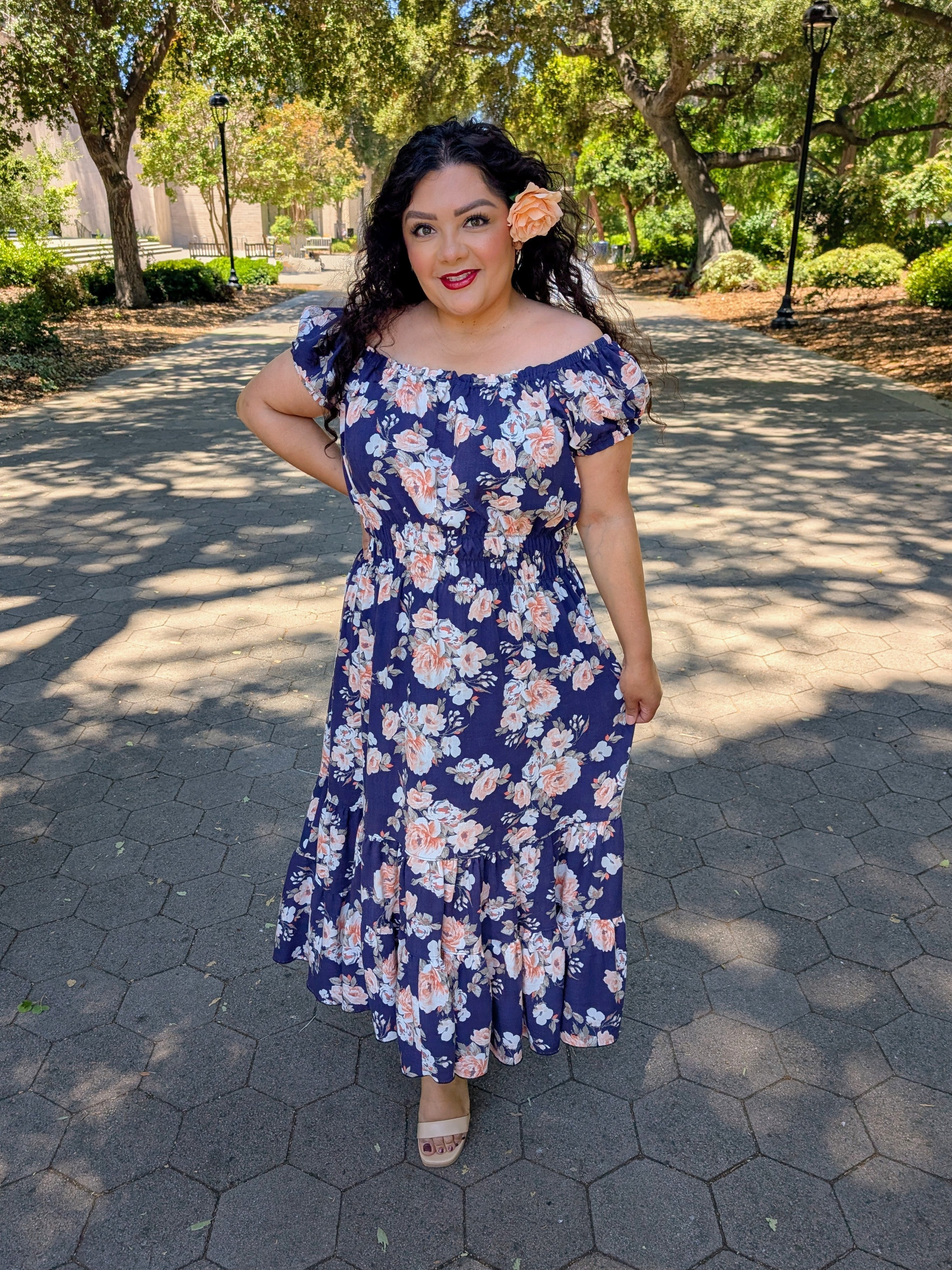 Woman in a woven blue floral midi dress standing on a paved path with trees in the background. PDF sewing patterns with instant download.