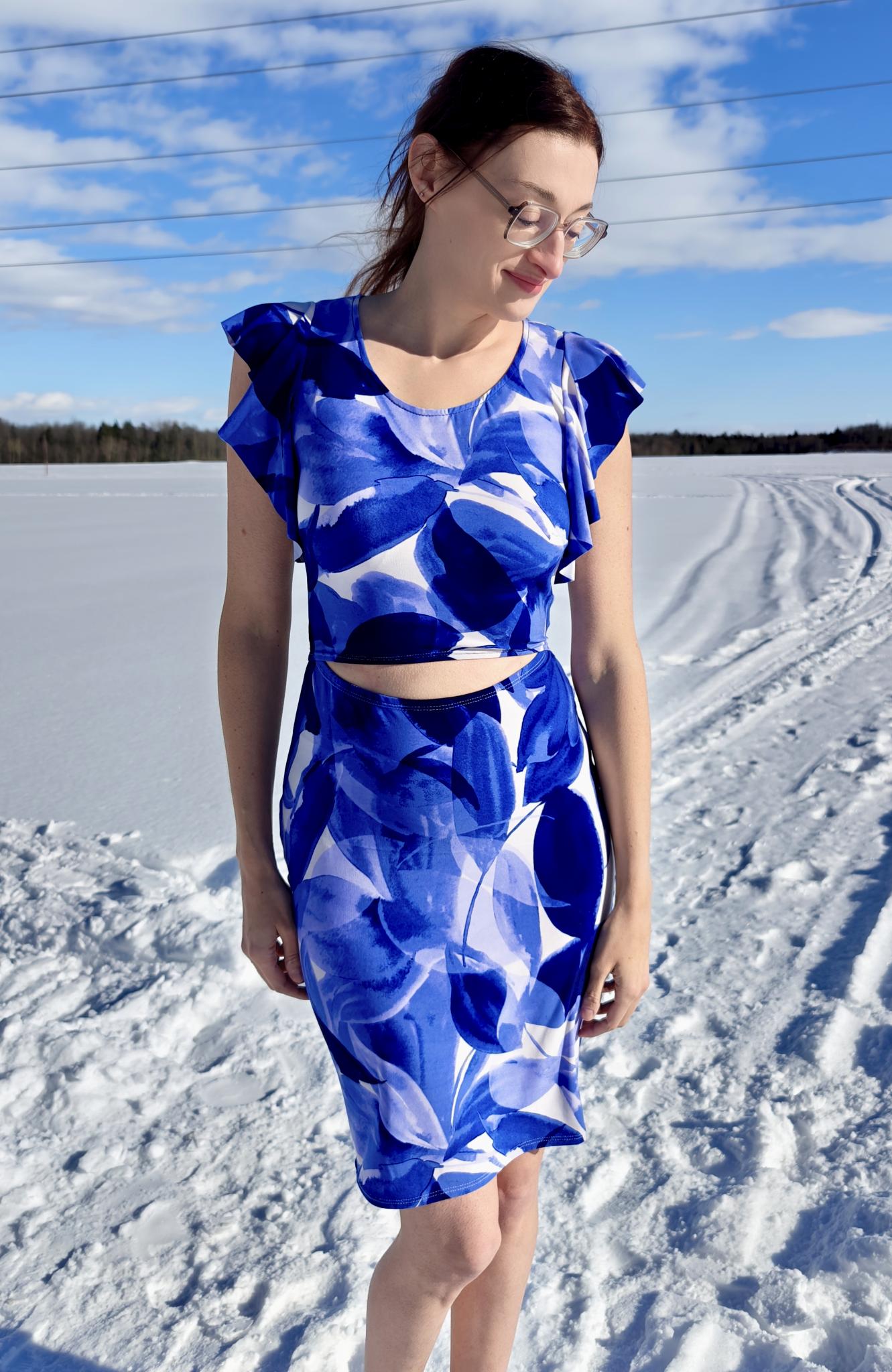 Woman wearing a blue and white patterned dress standing in a snowy landscape.