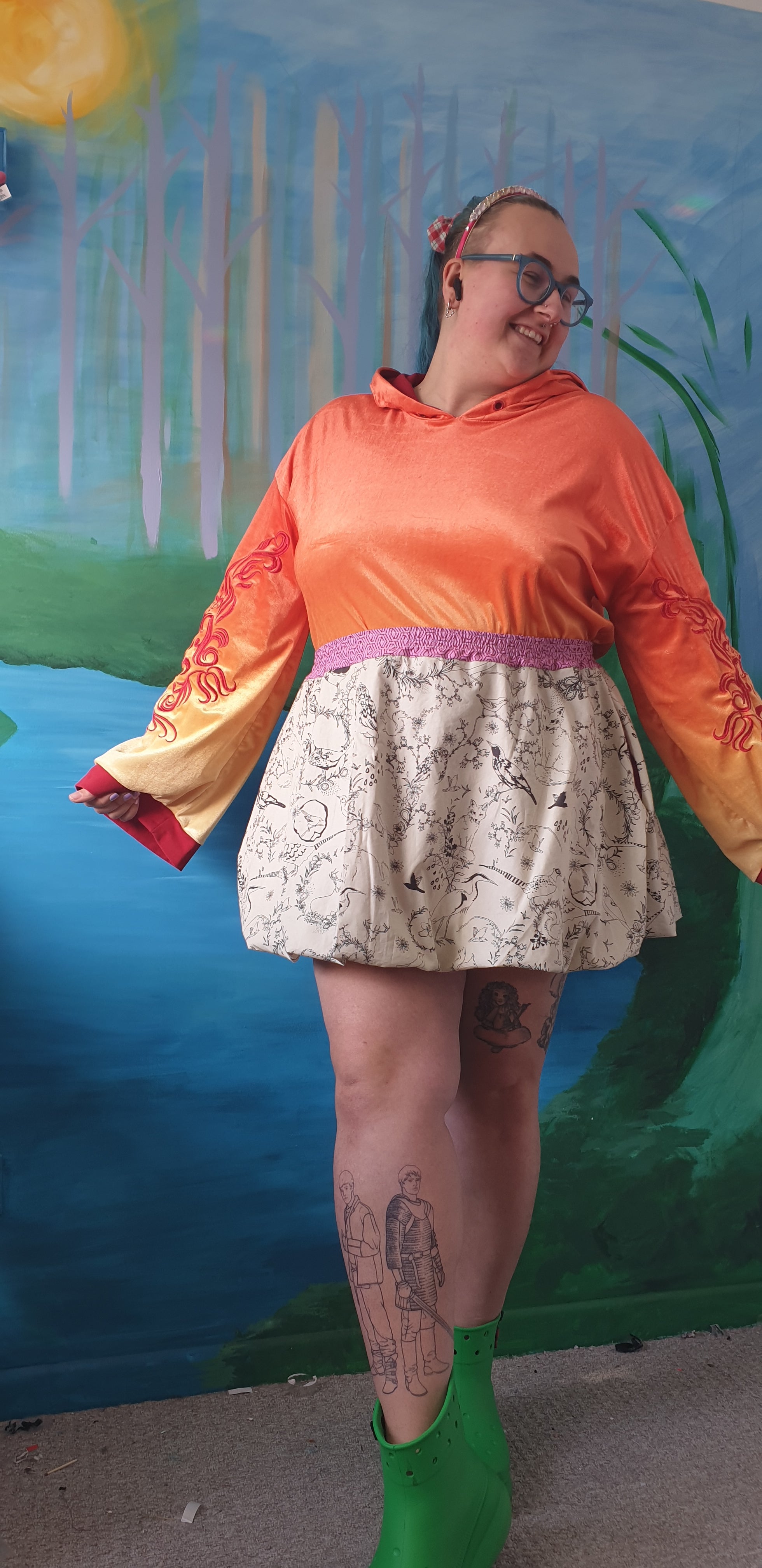 Person wearing an orange top and patterned bubble skirt with a colorful background.