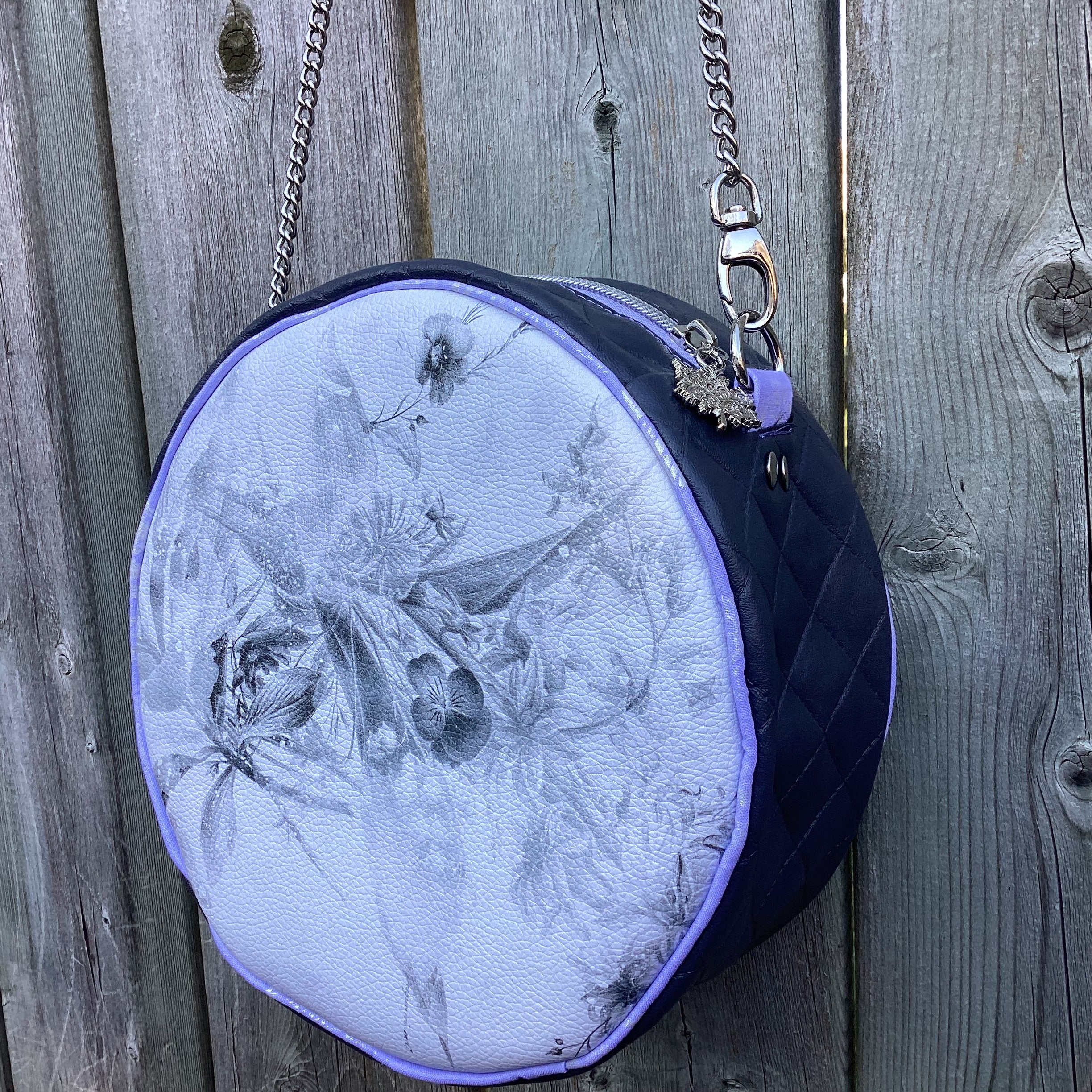 Round handbag with floral design and purple accents on a wooden surface