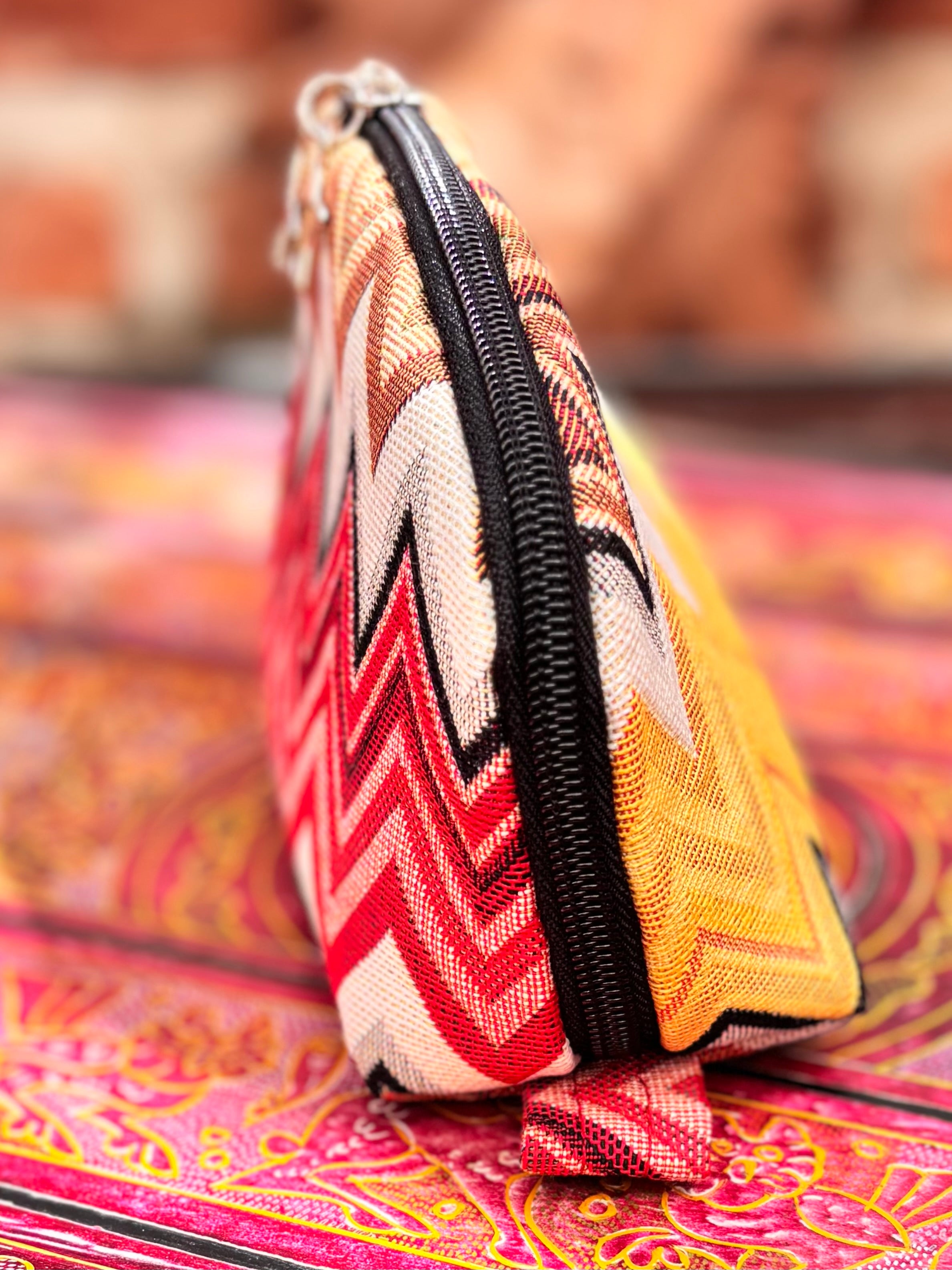 Colorful woven pouch, made with the Tessa pouch pattern, with a zigzag pattern on a patterned surface
