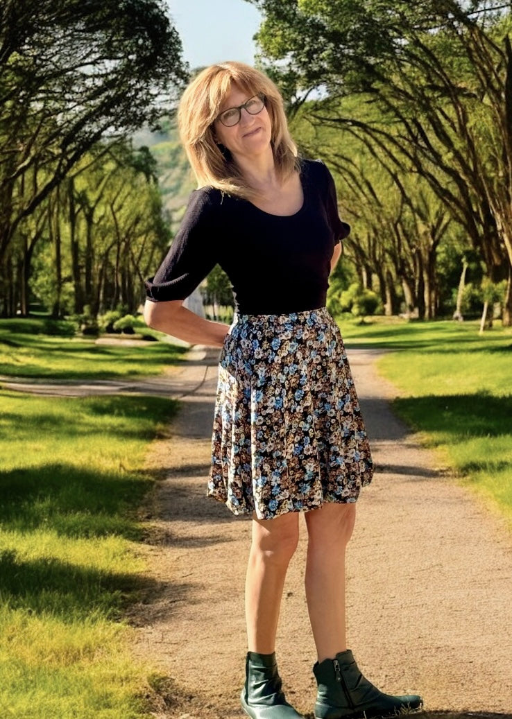Woman standing on a path in a park wearing a black puff sleeve top and floral bubble skirt. Handmade outfit.