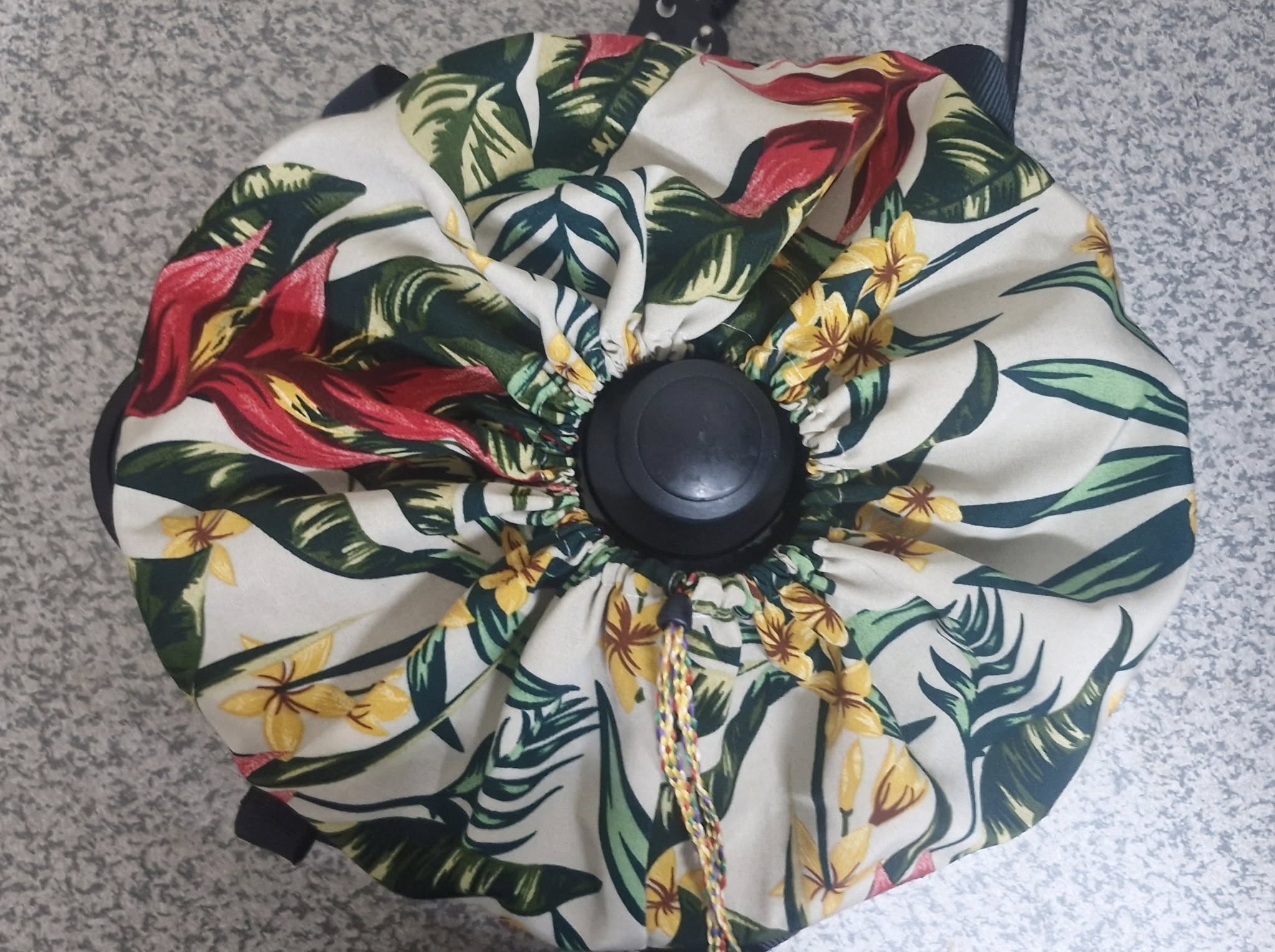 Floral-patterned slow cooker carrying bag with a black handle on a gray surface.