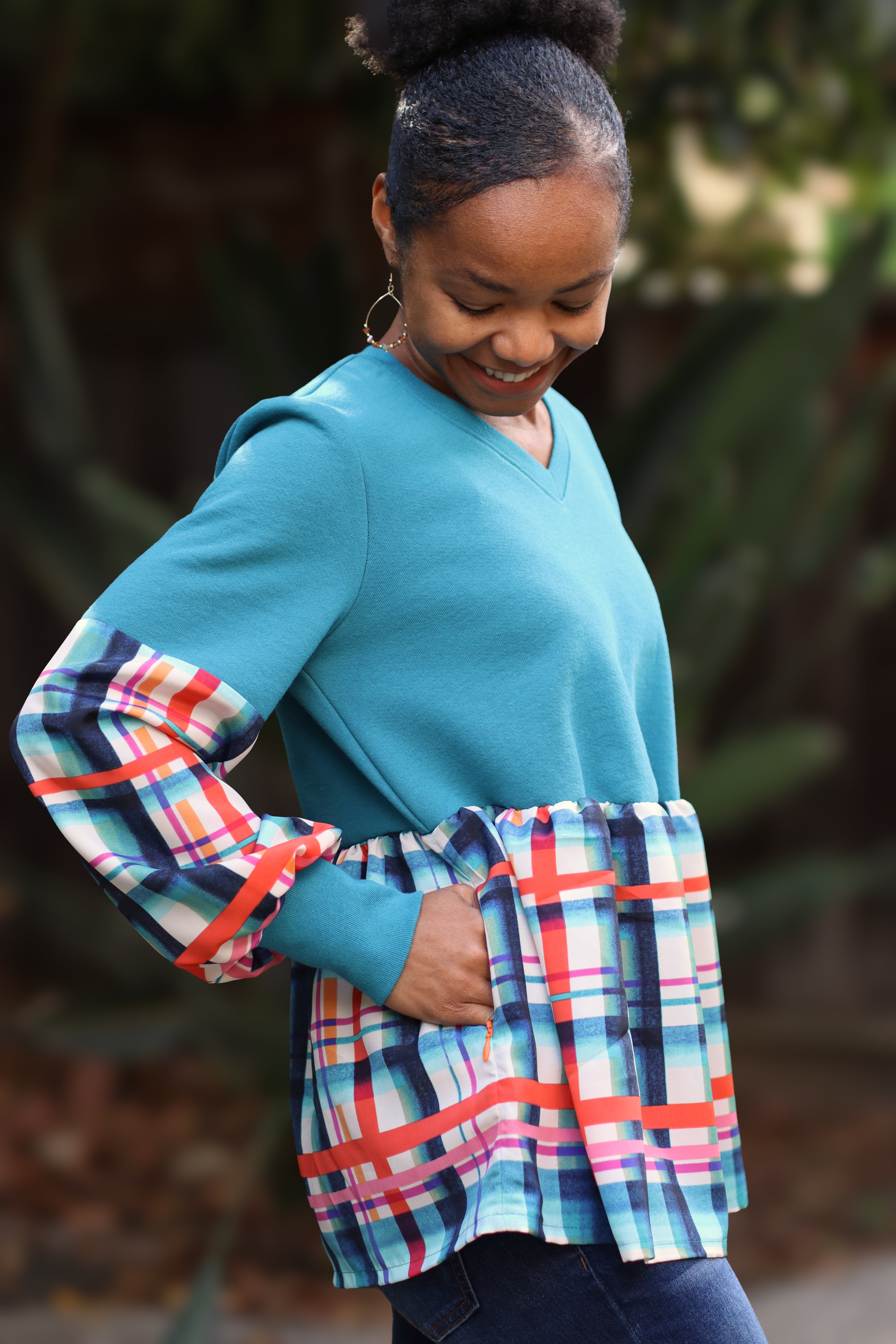 Woman wearing a blue with plaid sleeves and a matching skirt boho peasant top outdoors. Made using the Imogen mixed media peasant top sewing pattern. Invisible zipper pocket option.