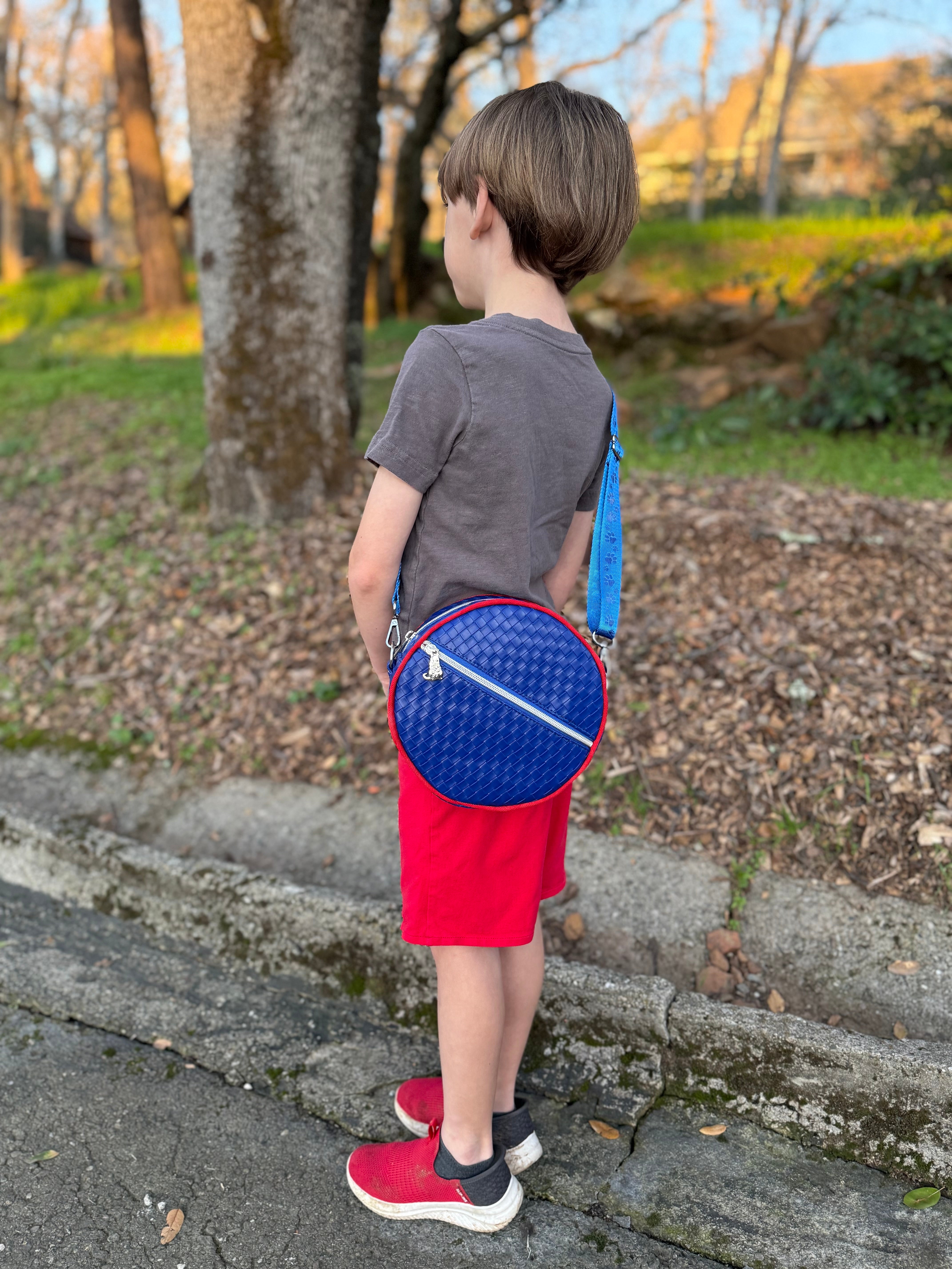 Child holding a blue and red round bag outdoors