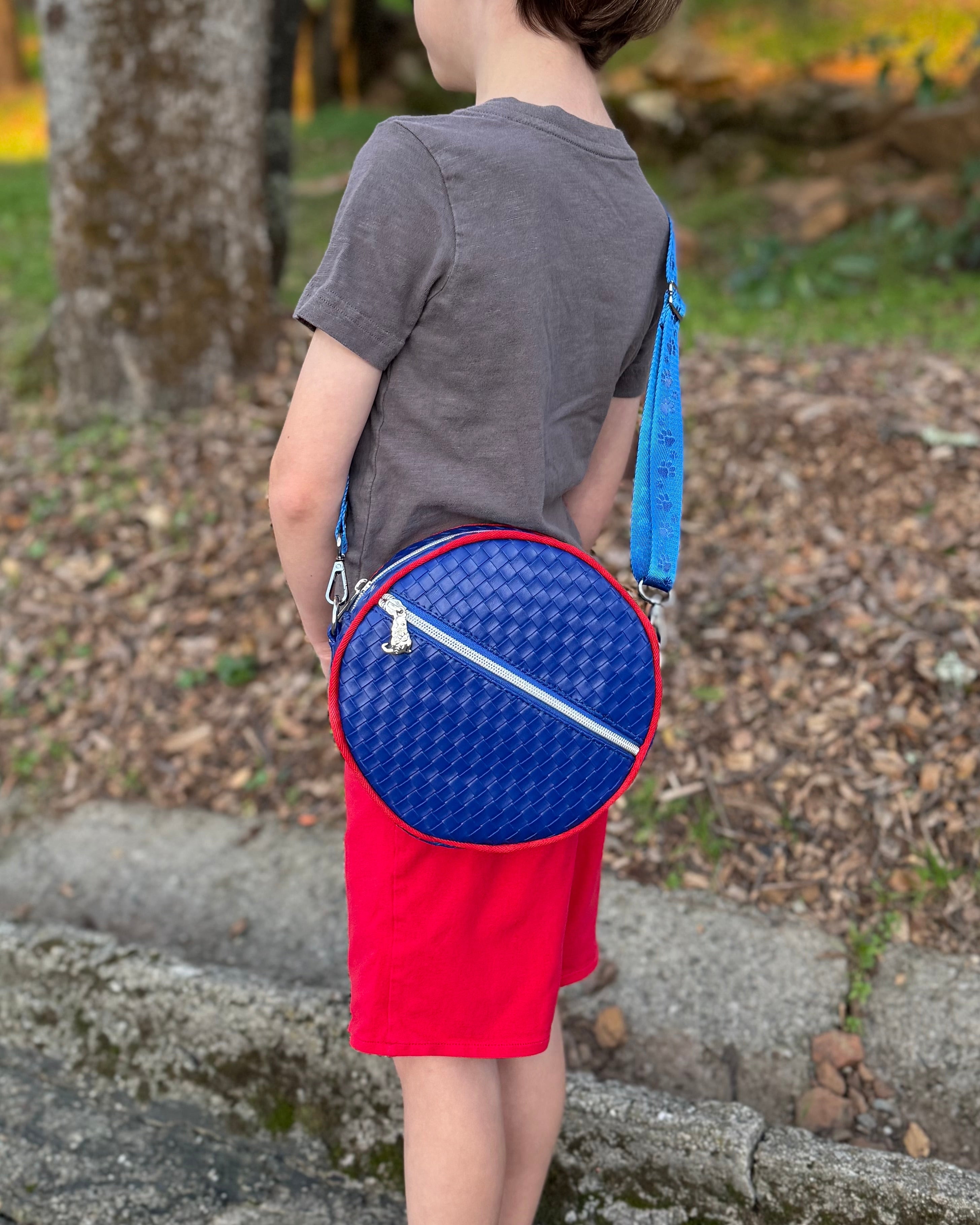 Child holding a blue and red round bag outdoors
