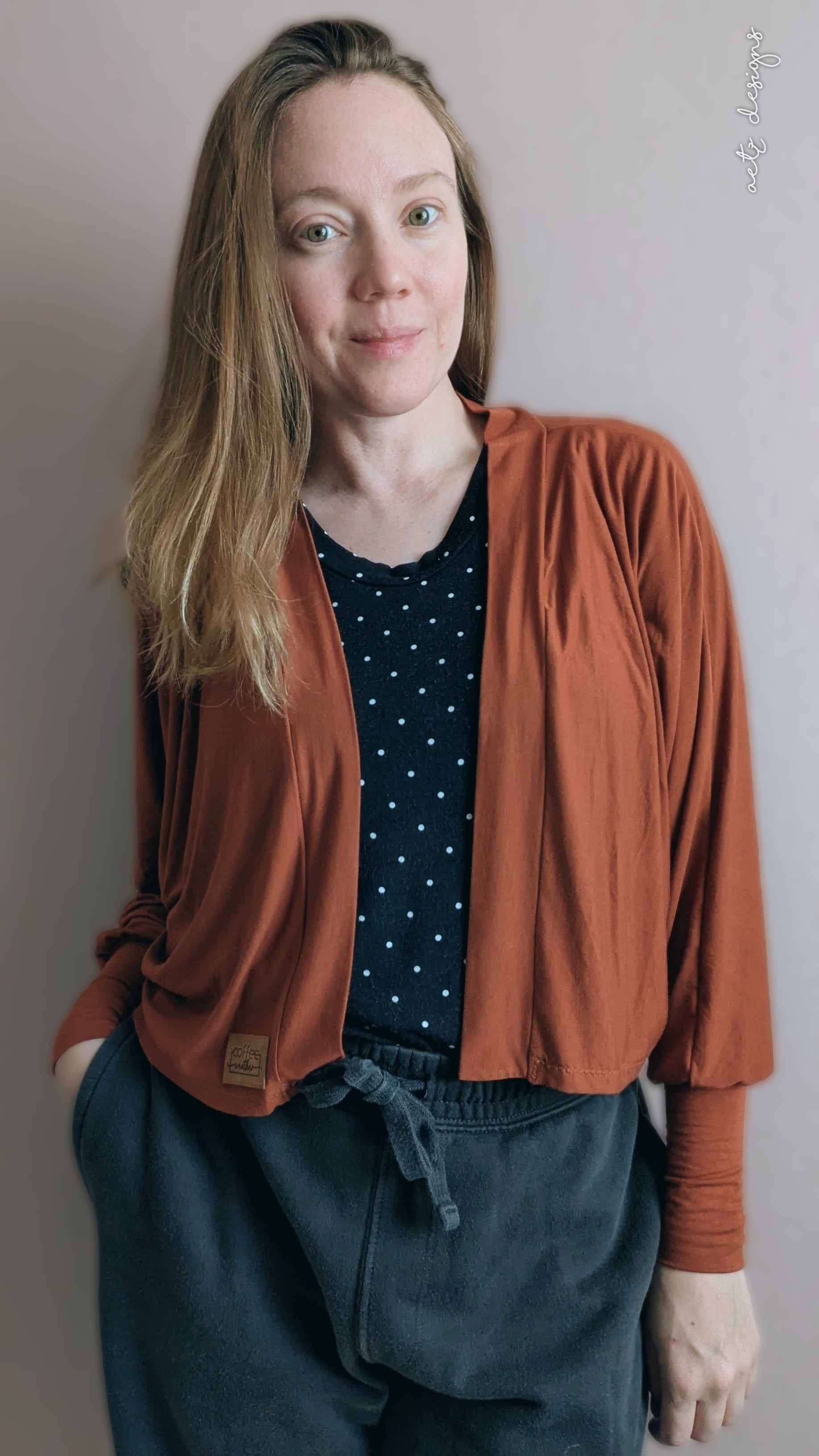 Handmade rust color batwing cardigan with open front and relaxed fit worn by a woman with shoulder length hair.