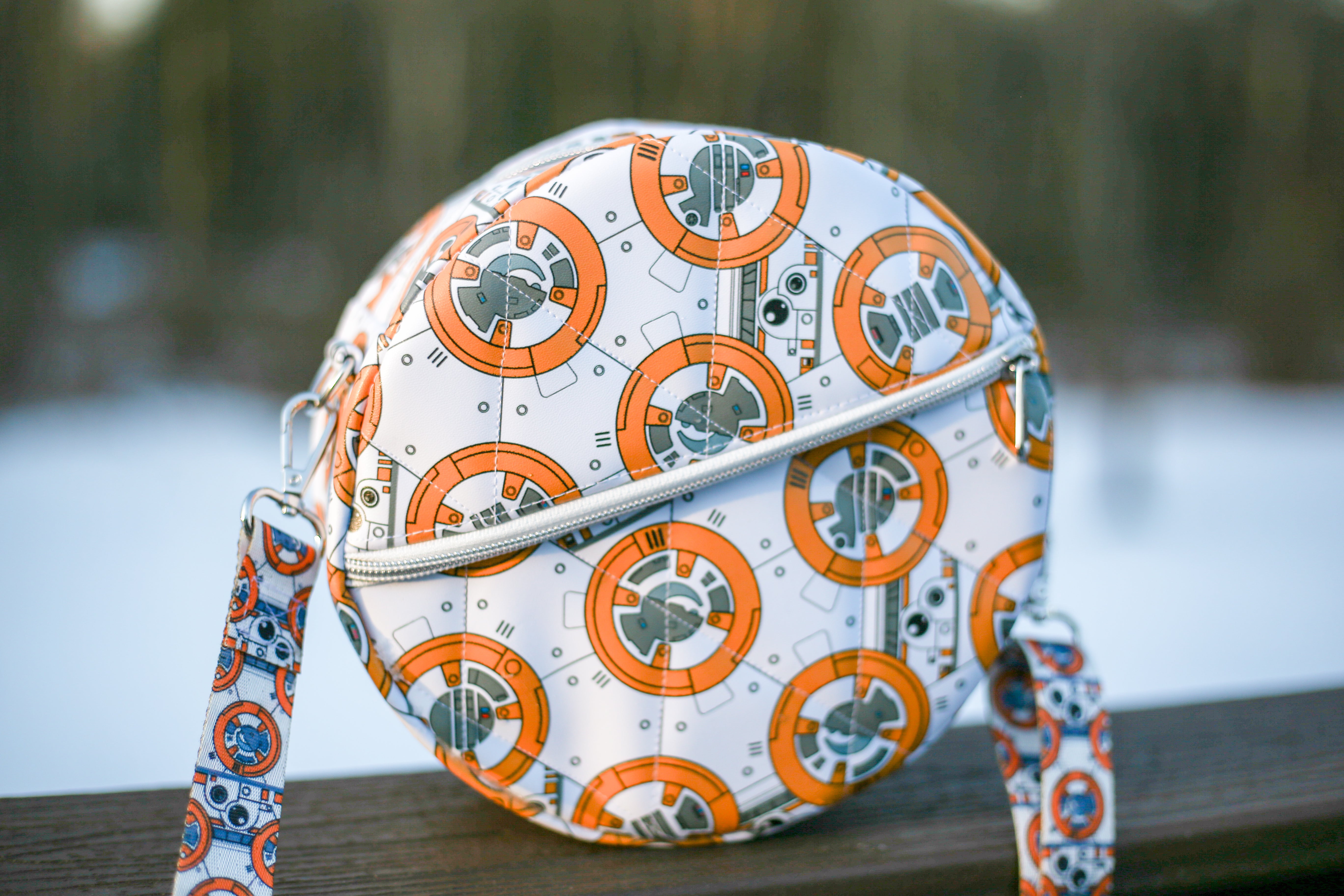 Round purse pattern with BB-8 design on a wooden surface with a blurred natural background. Front zip pocket.
