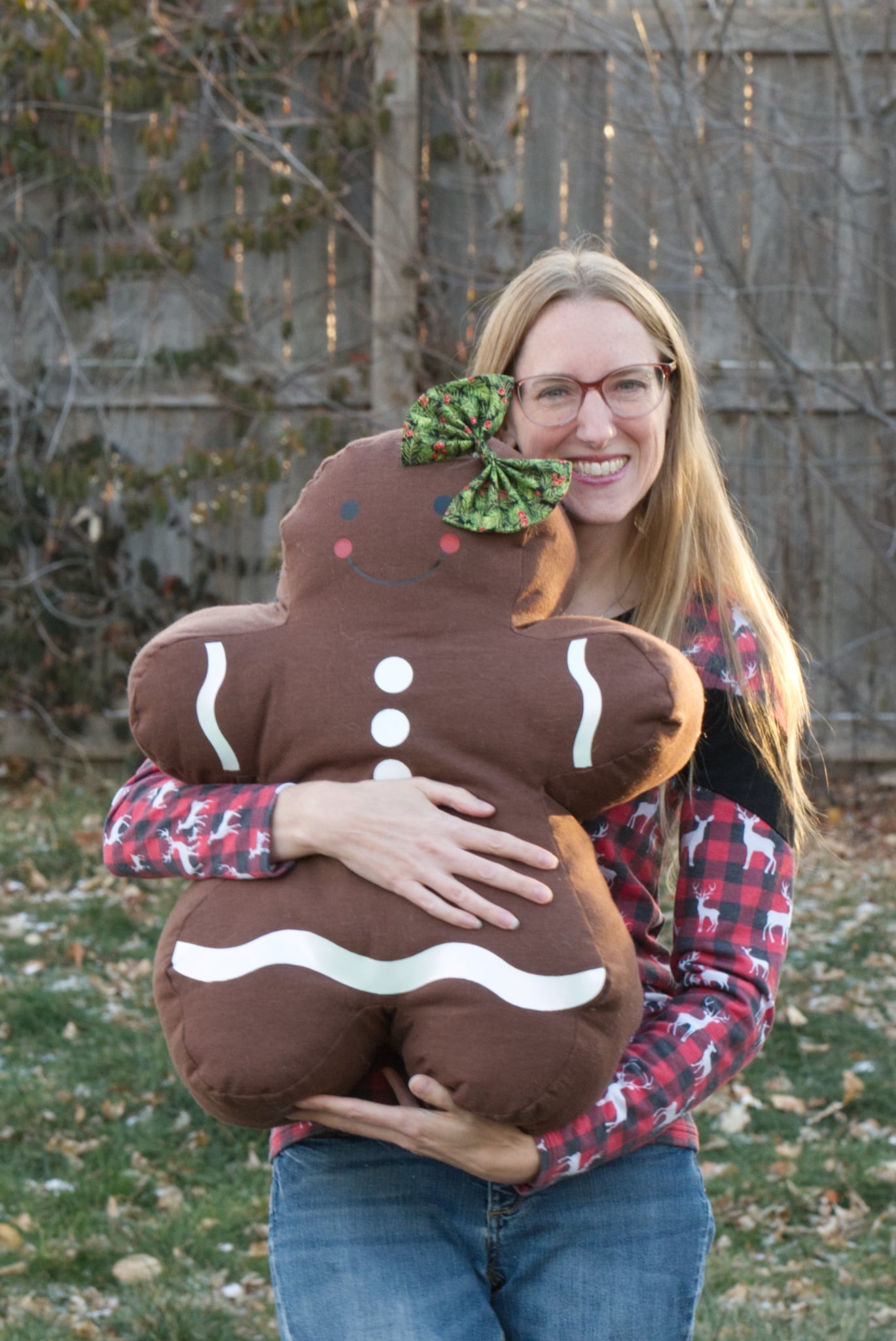 Person holding a large gingerbread man pillow outdoors.
