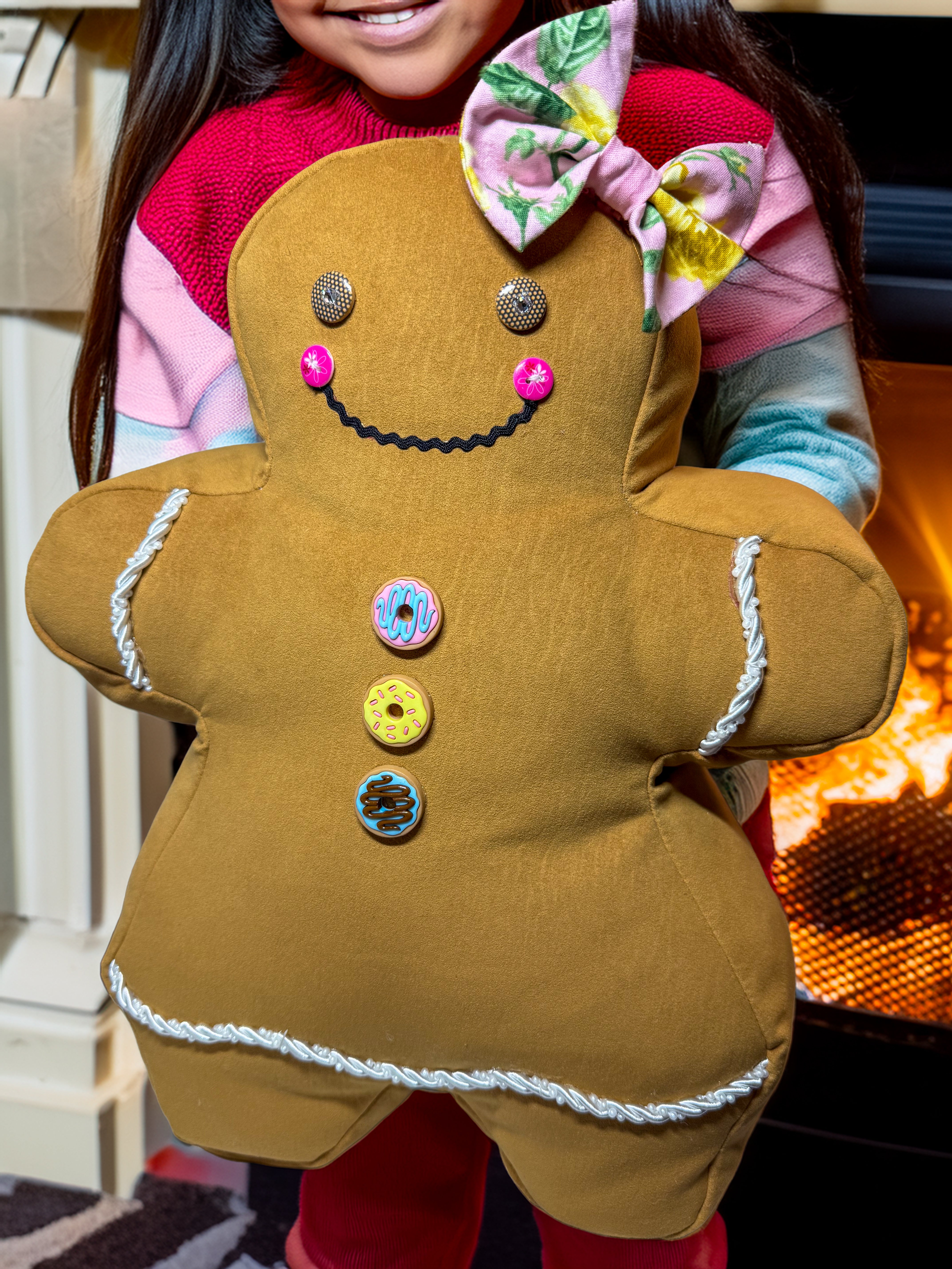 Person holding a gingerbread man plush toy with a colorful bow on top.