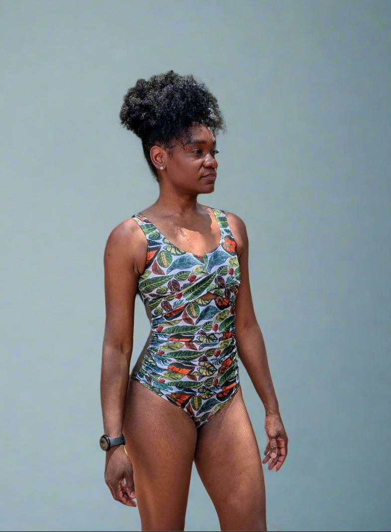 Woman wearing a colorful swimsuit standing outdoors with trees and a pool in the background