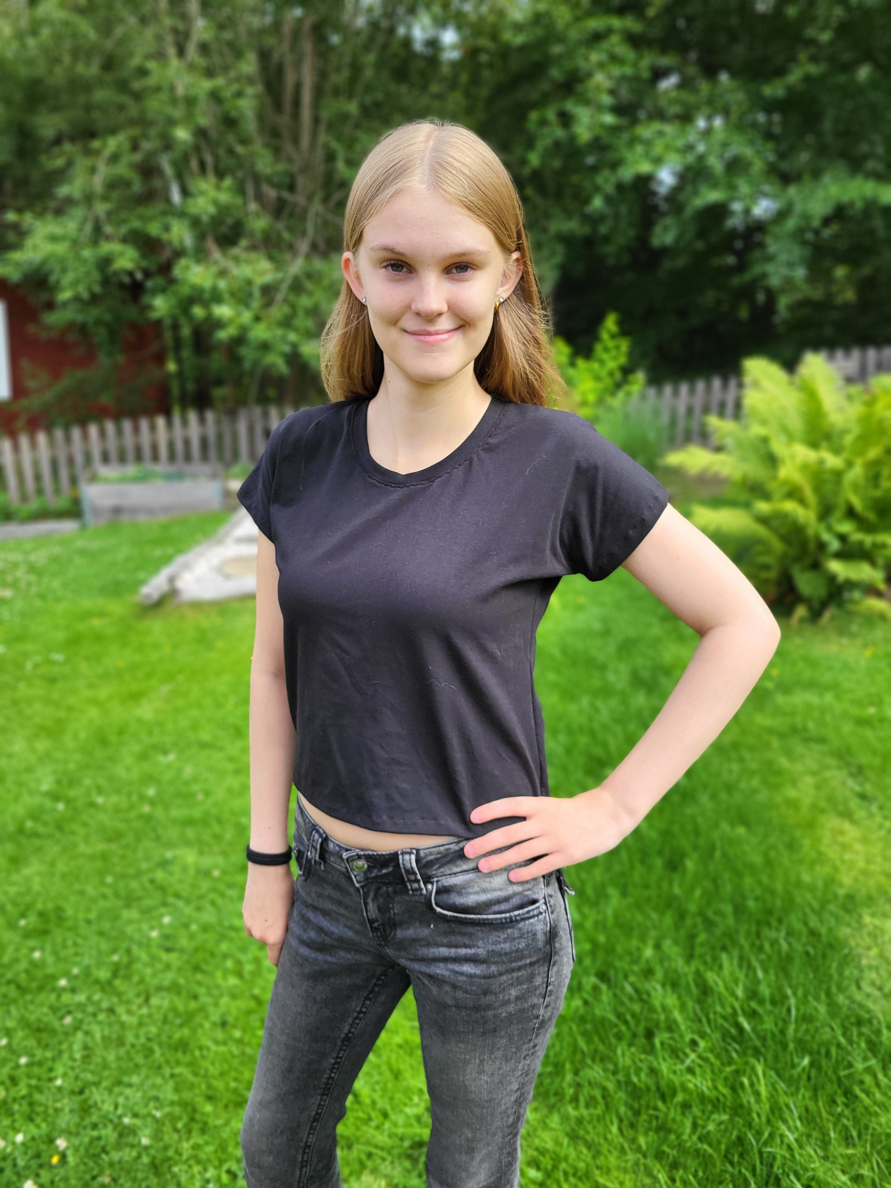 Teen girl standing on grass with trees in the background wearing a black crop dolman t-shirt made using Ellie and Mac Sewing Patterns.