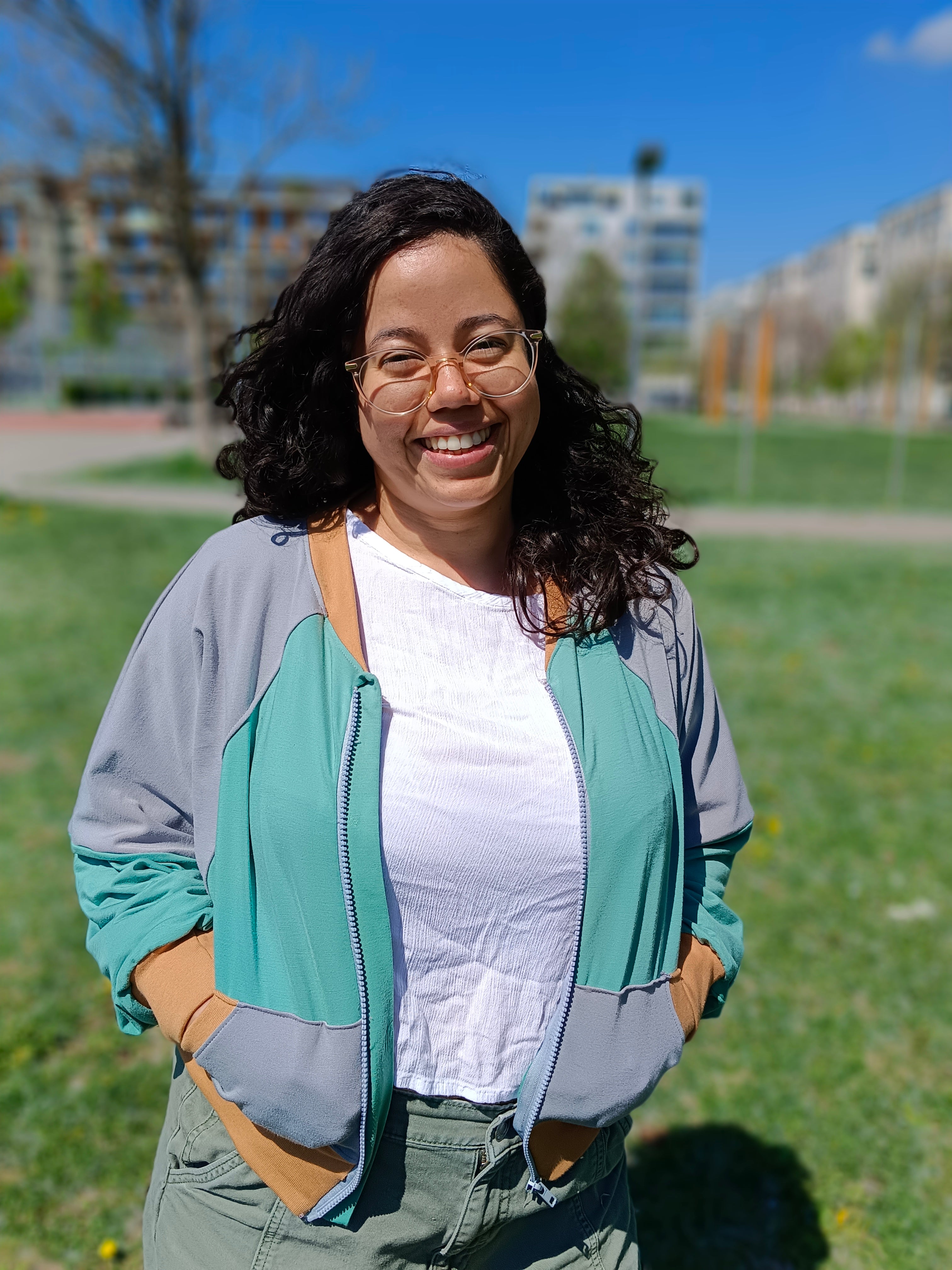 Woman outside modeling a color-blocked raglan bomber jacket with zip closure, kangaroo pocket detail, and cuffs. Easy pdf sewing pattern.