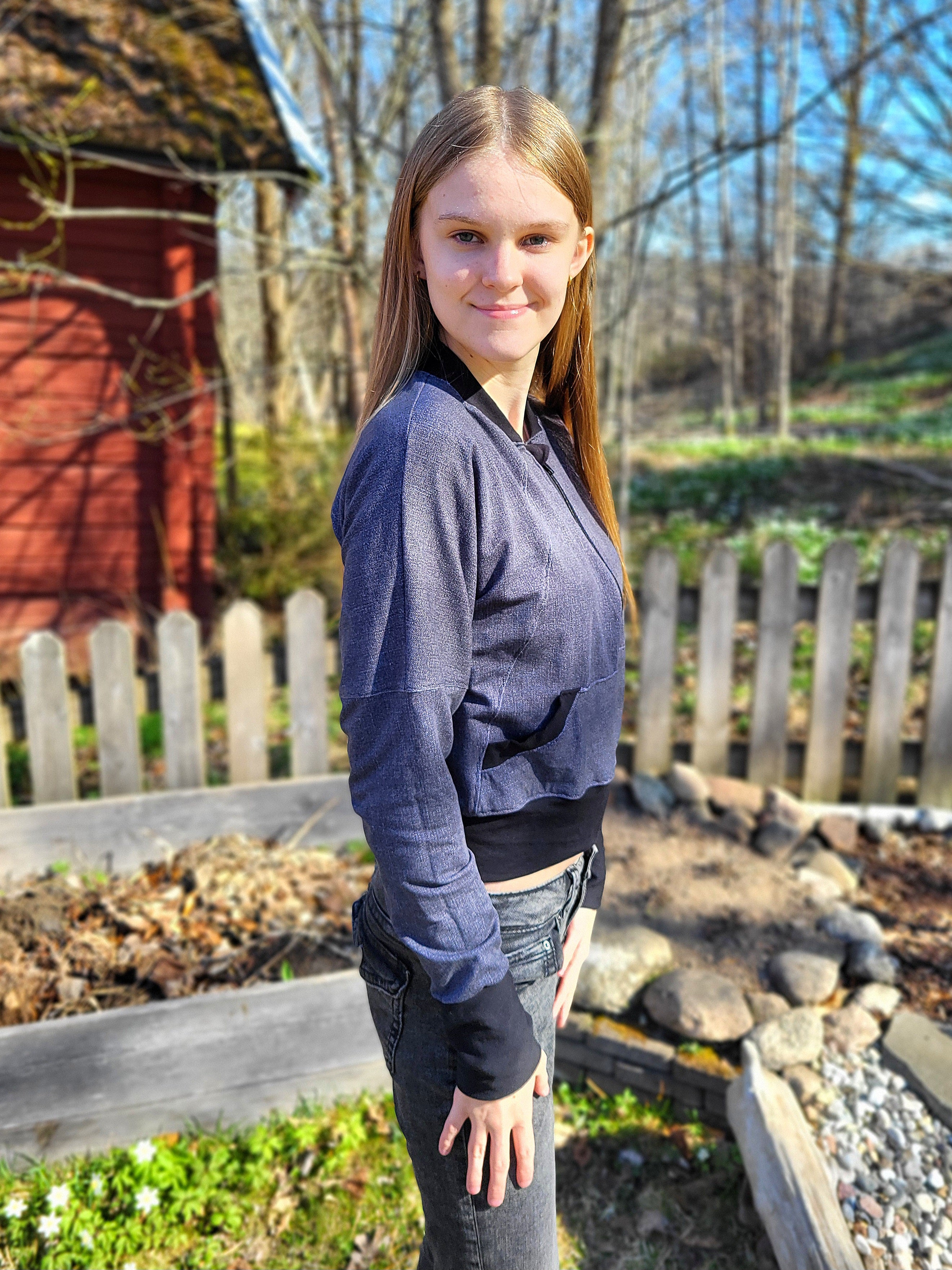 Teen girl wearing a denim knit fabric zip-up bomber jacket with raglan dolman sleeves, kangaroo pocket, and curved waistband. Knit fabric sewing pattern - instant download.