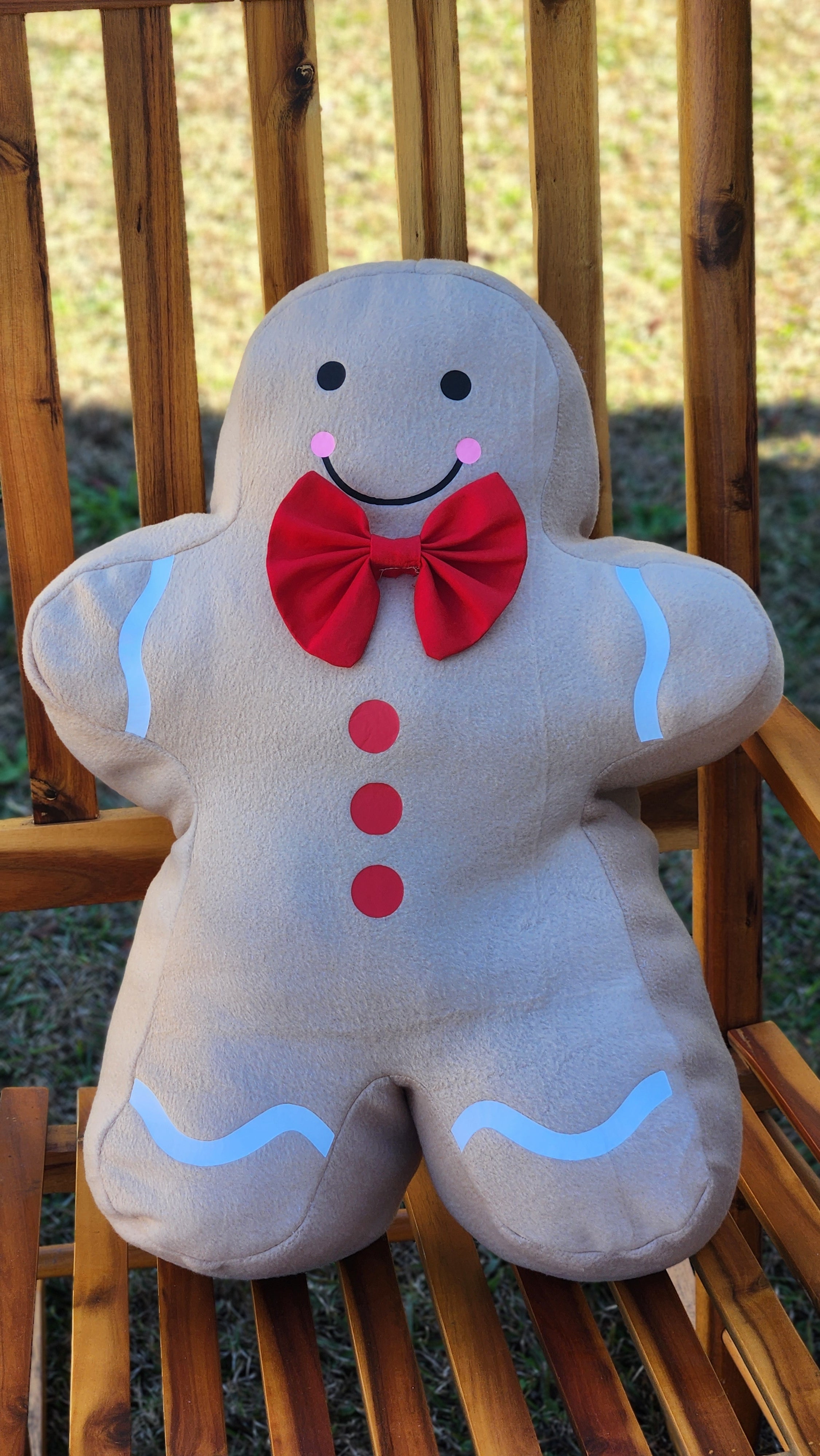 Plush toy shaped like a gingerbread man with a red bow on a wooden surface