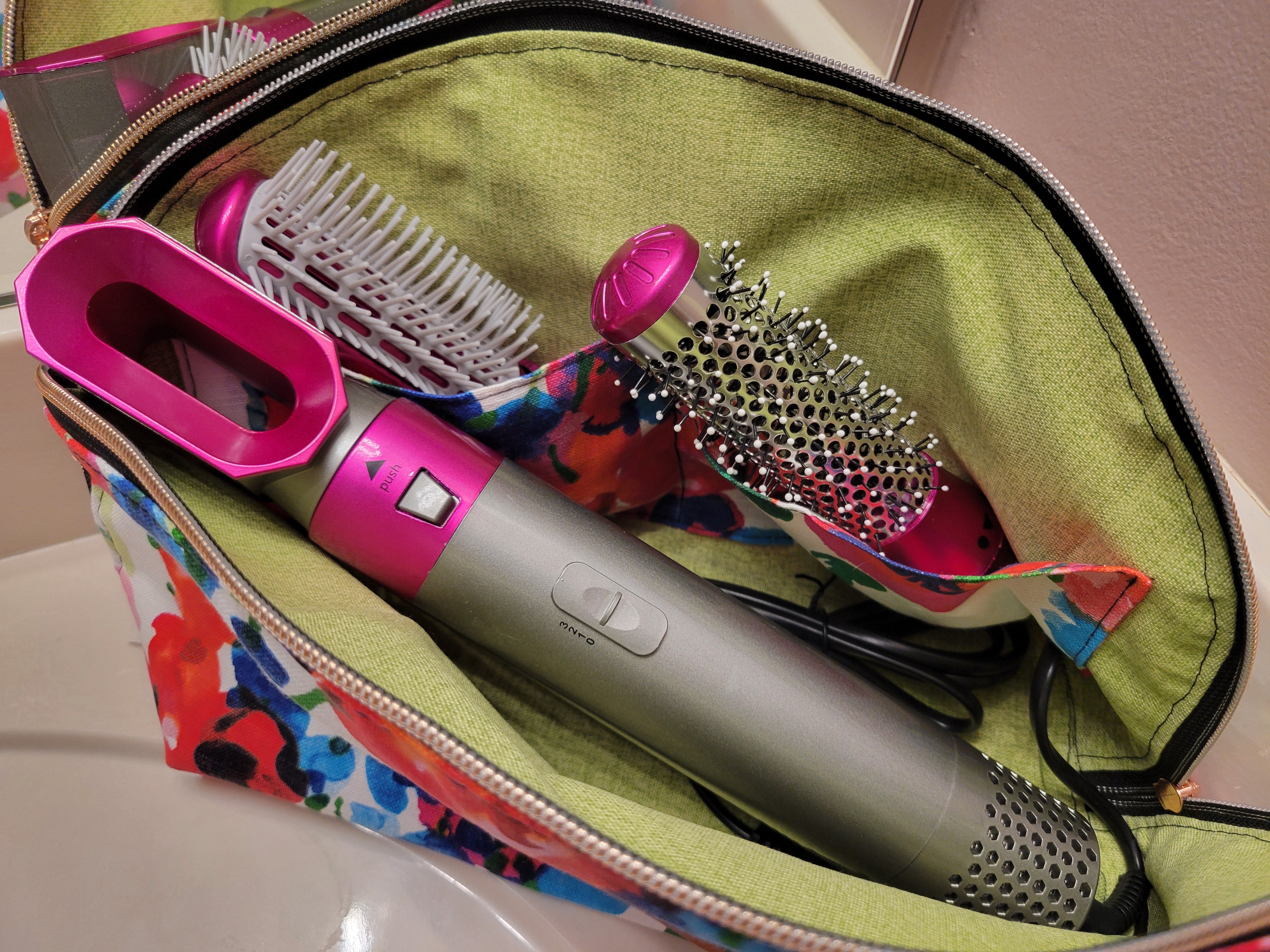 Hair styling tools including a hair dryer and brushes inside a colorful zippered pouch made using the Tessa Toiletry Pouch sewing pattern.