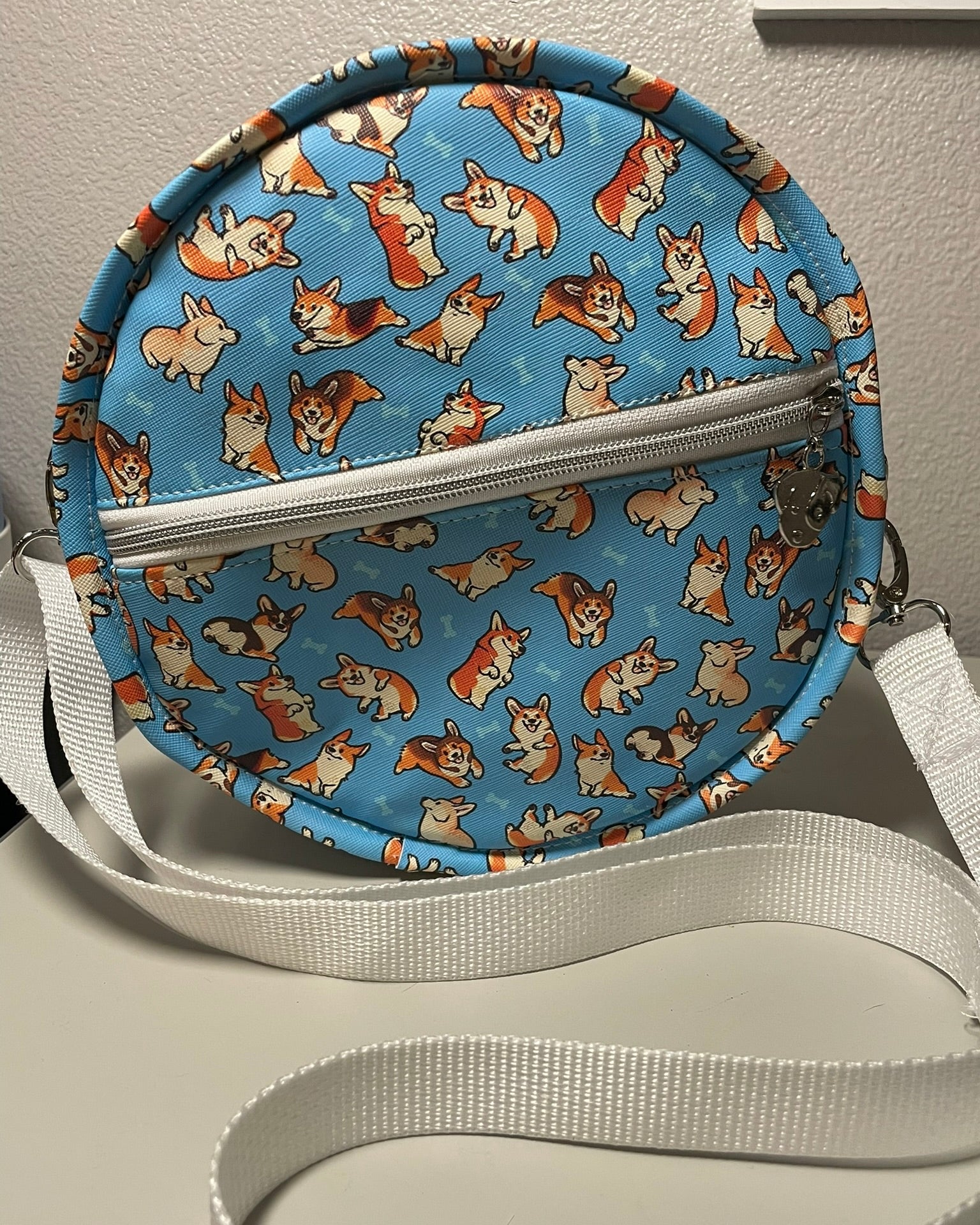 Round crossbody bag with corgi pattern on a flat surface