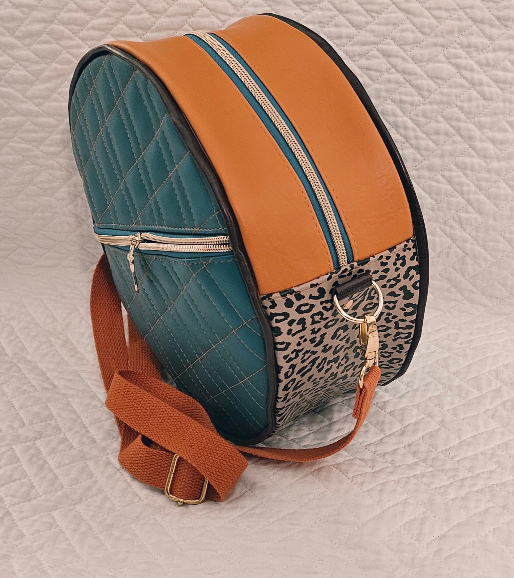 Multicolored round purse with leopard print accent on a textured surface.